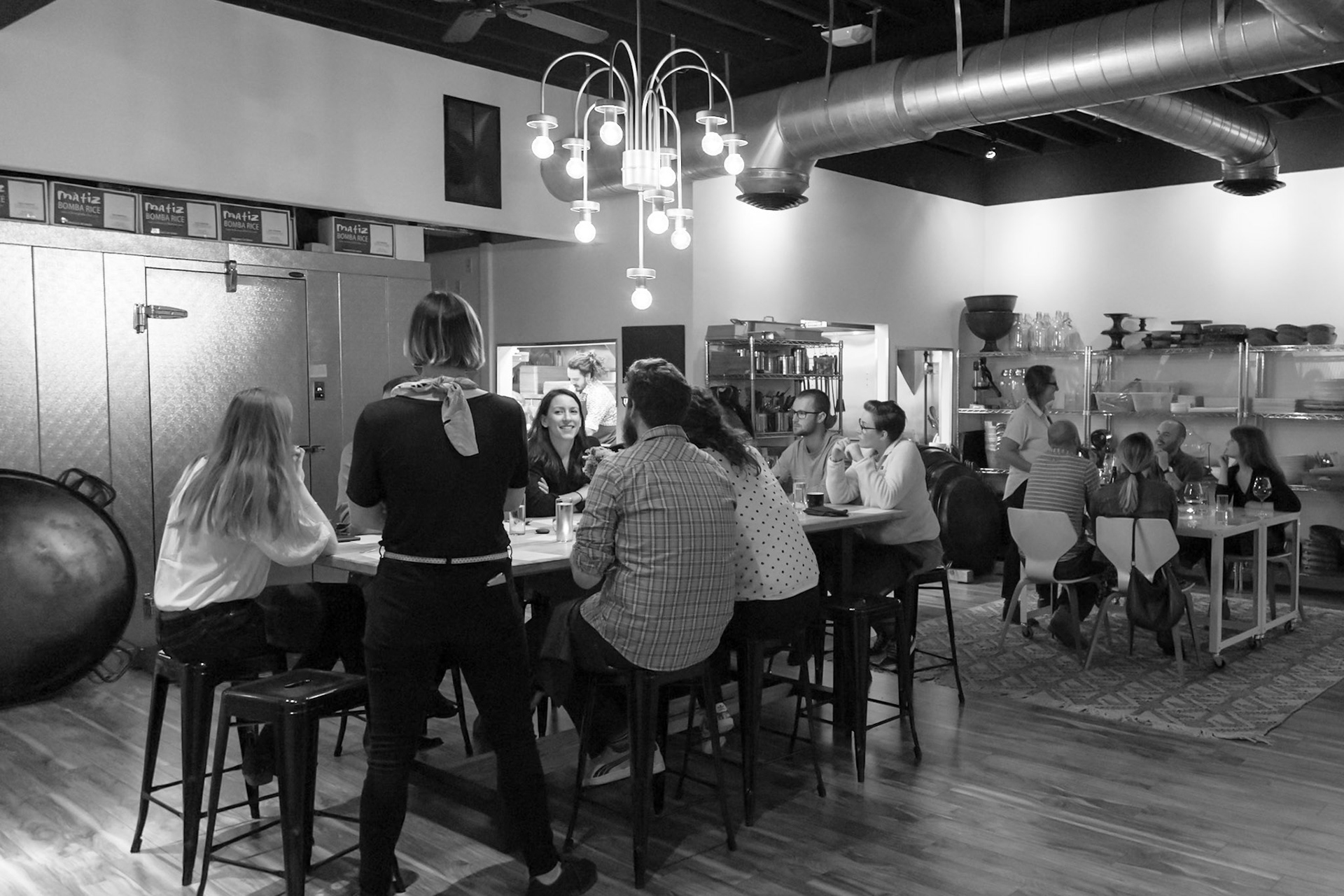 Fog Lark, Portland, Oregon - April 6th 2018: Diners enjoy a meal at a restaurant, with staff serving and preparing food in the background.