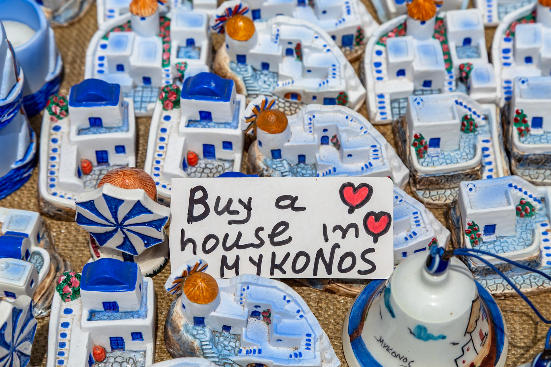 Mykonos, Greece - May 22nd 2018: Souvenir vendor selling miniature Mykonos houses, encouraging tourists to "Buy a house in Mykonos".