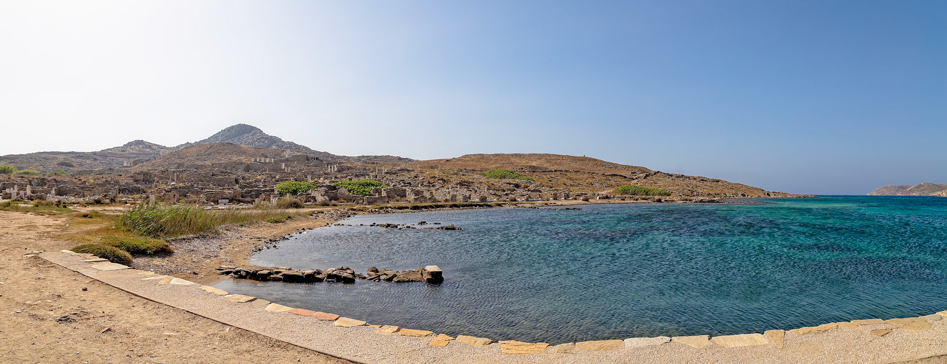 Delos, Greece - May 22nd 2018: A scenic view of the ancient ruins of Delos, a UNESCO World Heritage site, nestled along the Aegean Sea, showcasing its historical and natural beauty.
