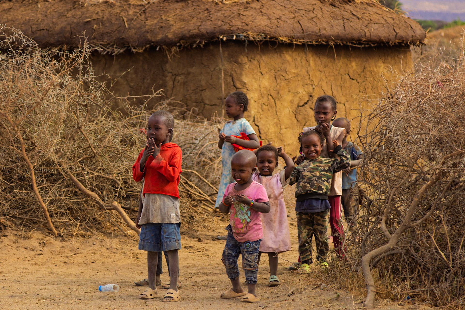 Maasai children gather outside a traditional home in their village in Kenya, curious about the camera.