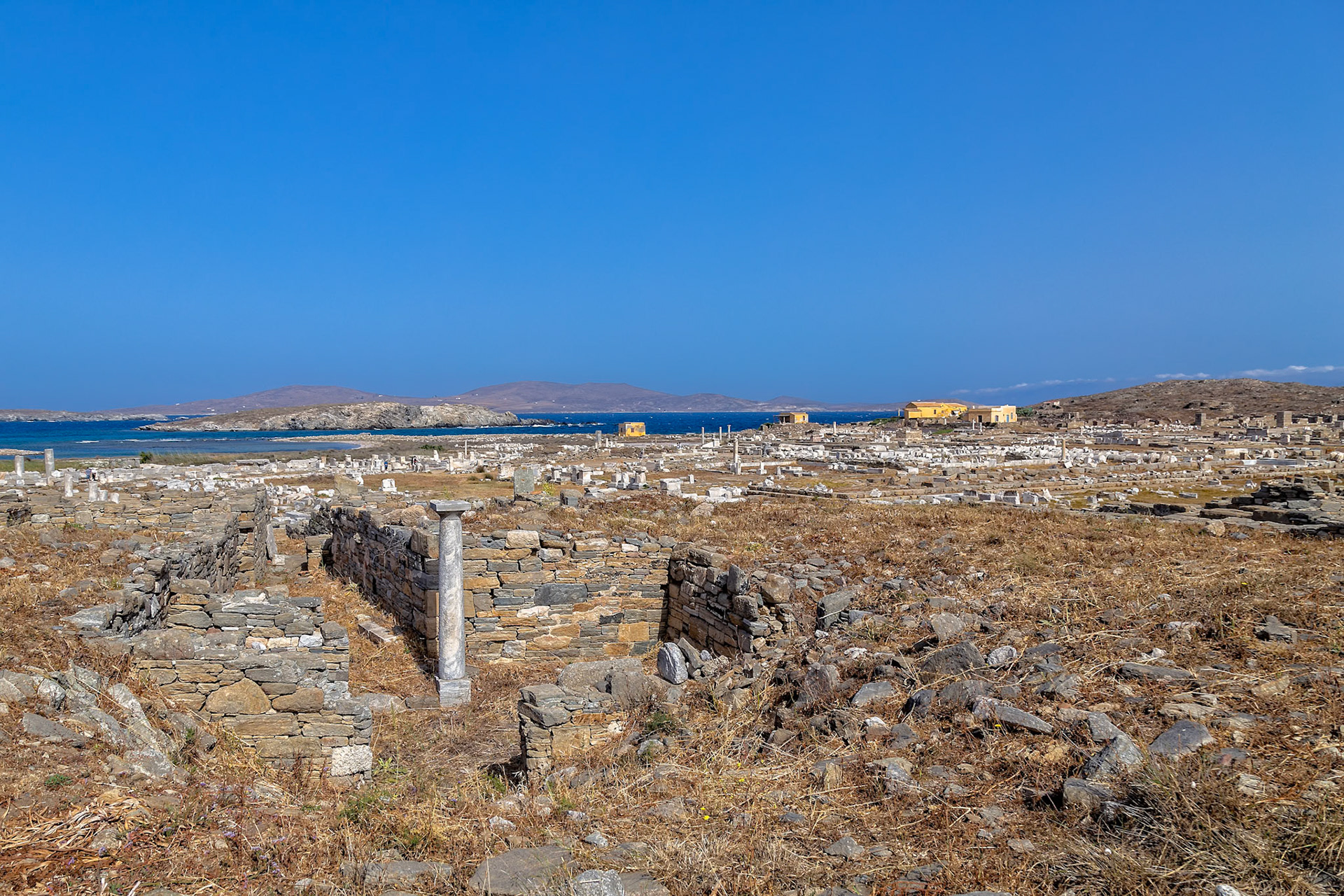 Delos, Greece - May 22nd 2018: Ruins of ancient buildings stand on Delos, a Greek island and archaeological site. The ruins are preserved for historical and cultural reasons.