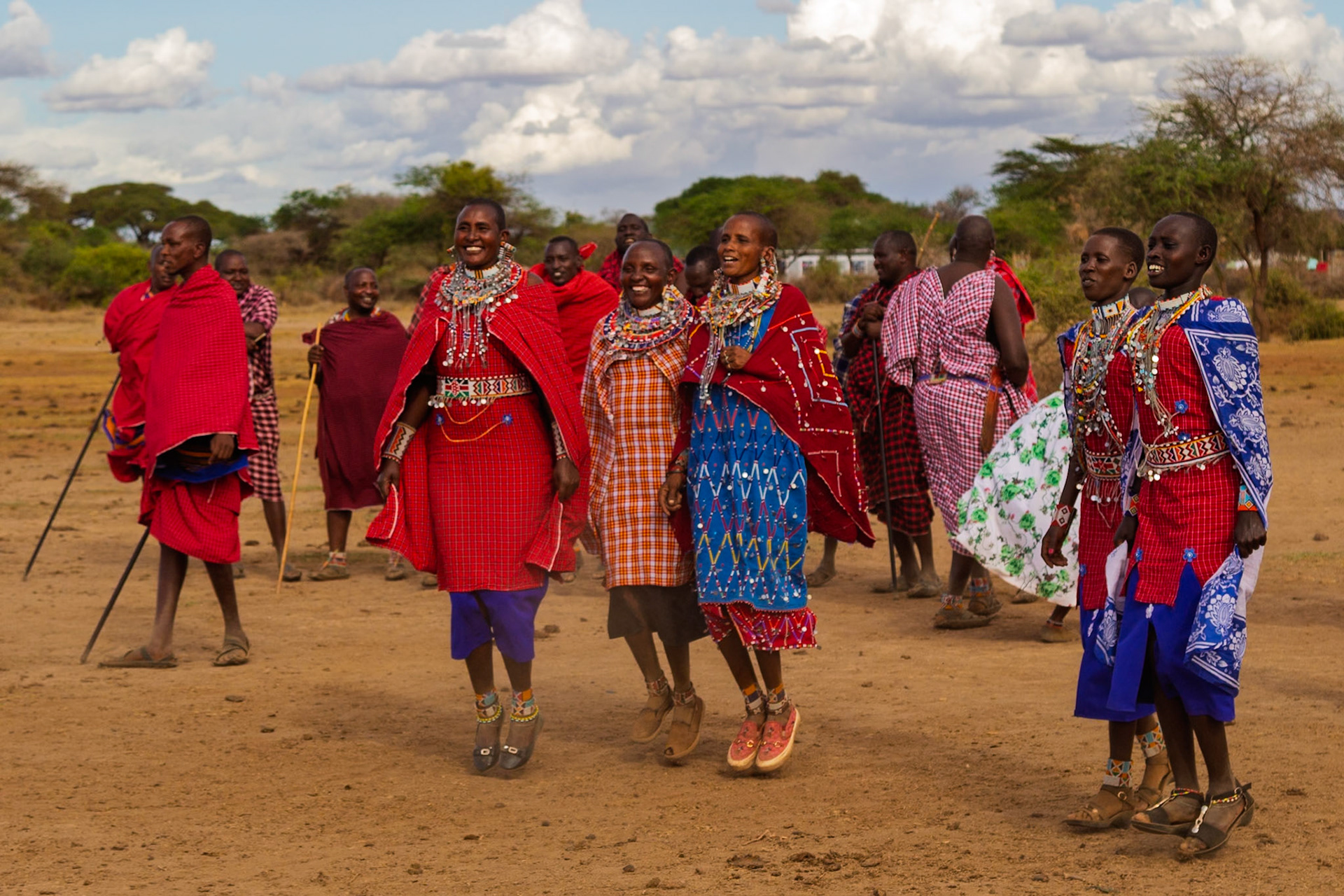 Maasai people in Kenya are seen jumping and celebrating in their village, wearing traditional clothing and jewelry.