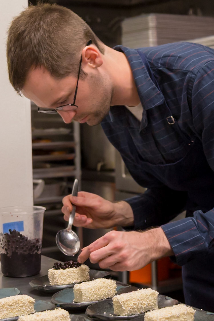 Fog Lark, Portland, Oregon - April 6th 2018: A chef carefully spoons blueberries onto desserts, adding a final touch to the dish.