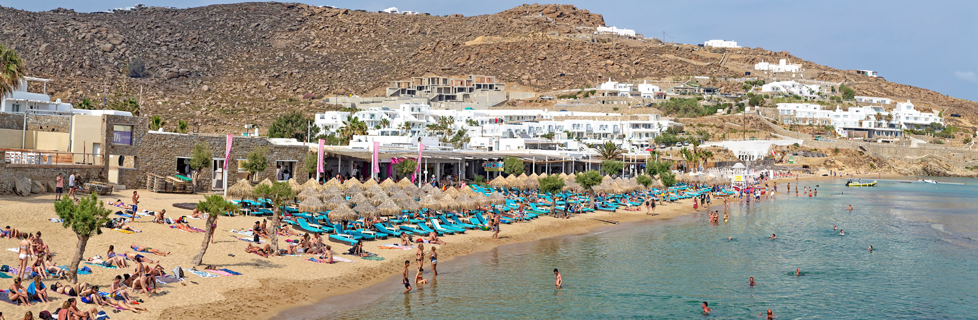 Paradise Beach, Mykonos, Greece - May 24th 2018: Beachgoers relax on sunbeds and swim in the Aegean Sea, enjoying the sun and scenery.