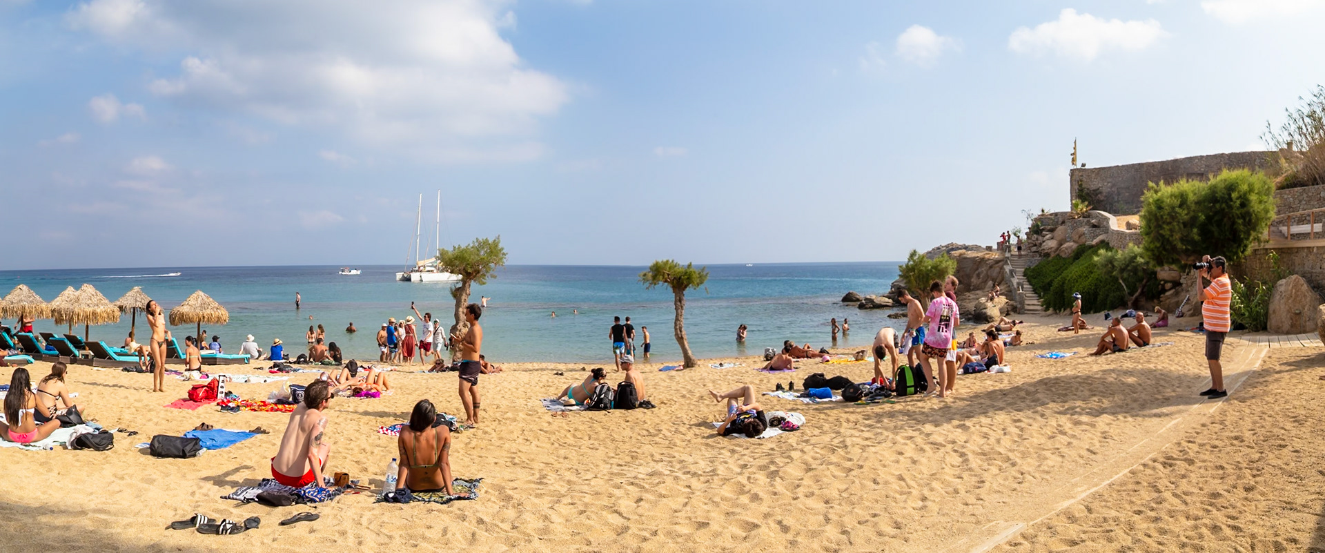 Paradise Beach, Mykonos, Greece - May 24th 2018: Beachgoers relax, swim, and take photos on a sunny day at Paradise Beach, enjoying the sand and sea.