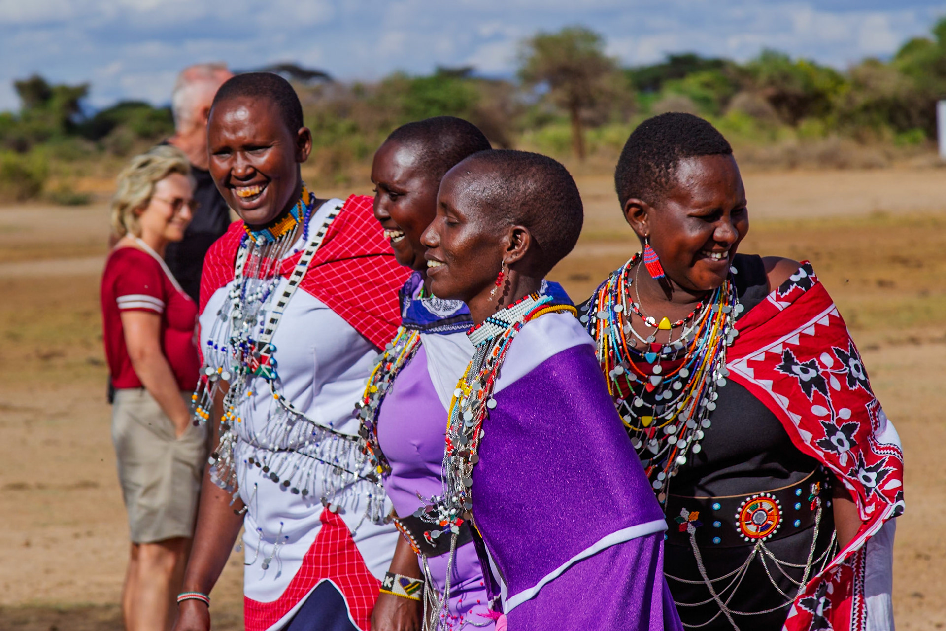 Maasai women in Kenya, adorned in traditional attire, share a joyful moment, showcasing their vibrant culture.