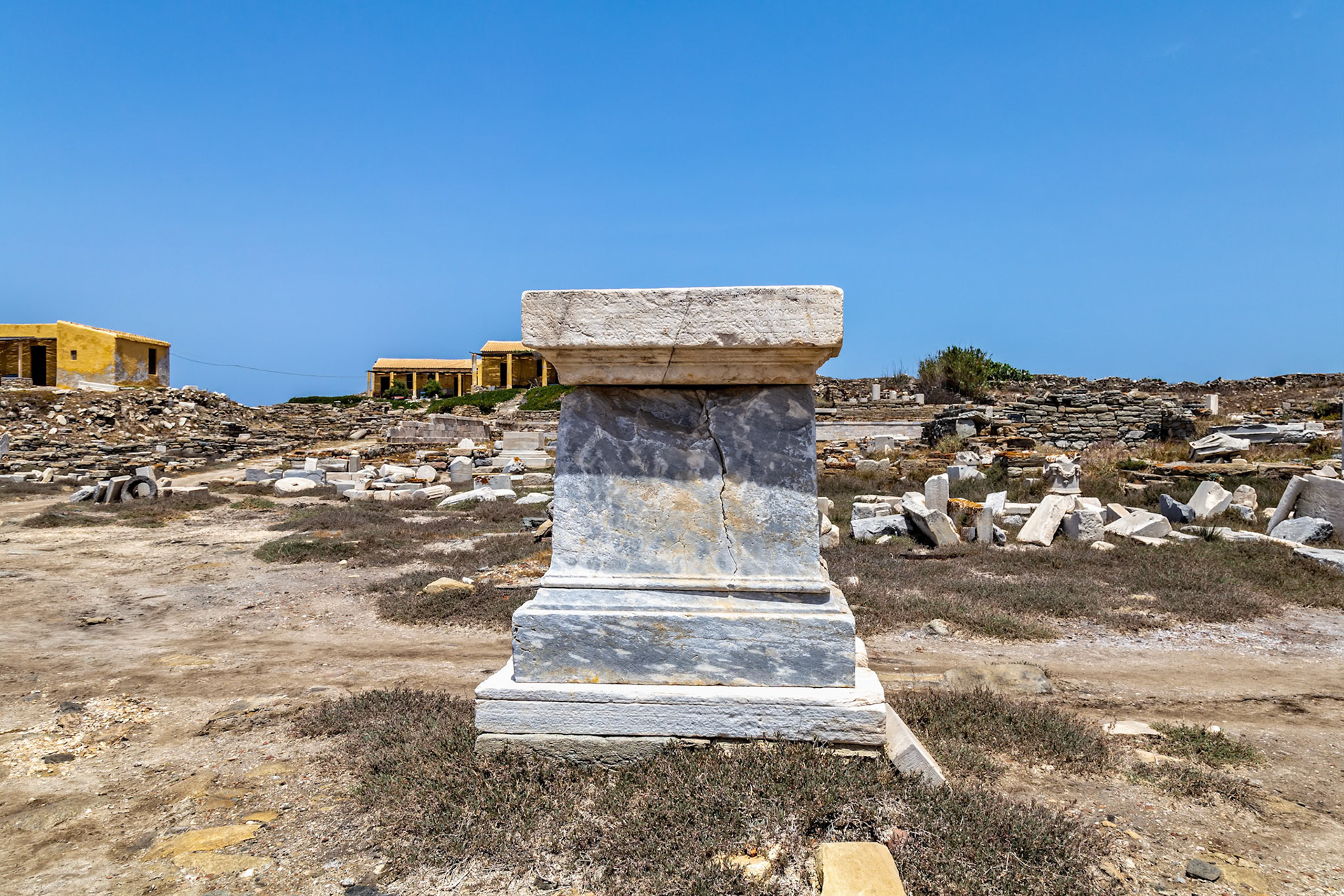 Delos, Greece - May 22nd 2018: A marble pedestal stands amidst the ruins of Delos, a UNESCO World Heritage site, showcasing the island's rich ancient history.