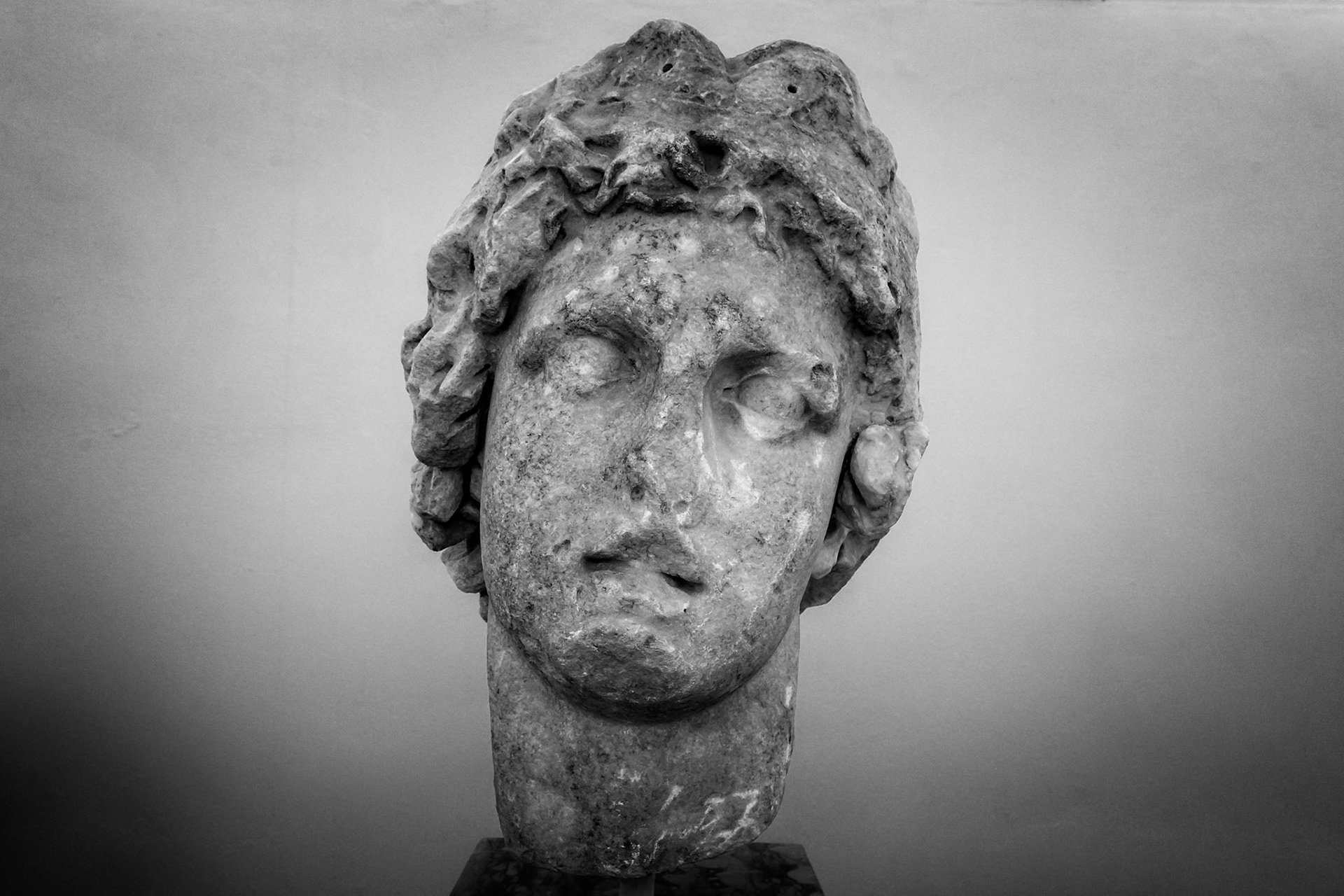 Delos, Greece - May 22nd 2018: A marble head of a young man, possibly a god or hero, is displayed. The sculpture showcases classical artistry and historical significance.