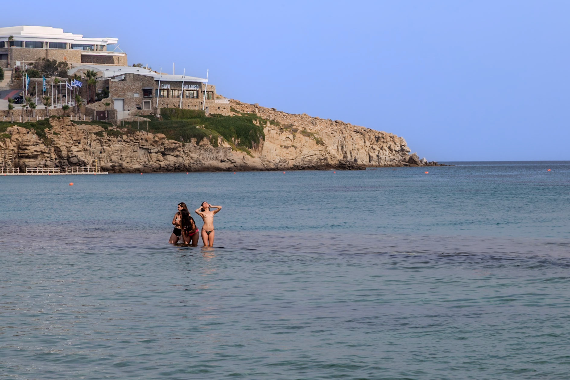 Paradise Beach, Mykonos, Greece - May 24th 2018: People are enjoying the cool water on a hot day at Paradise Beach in Mykonos, Greece.