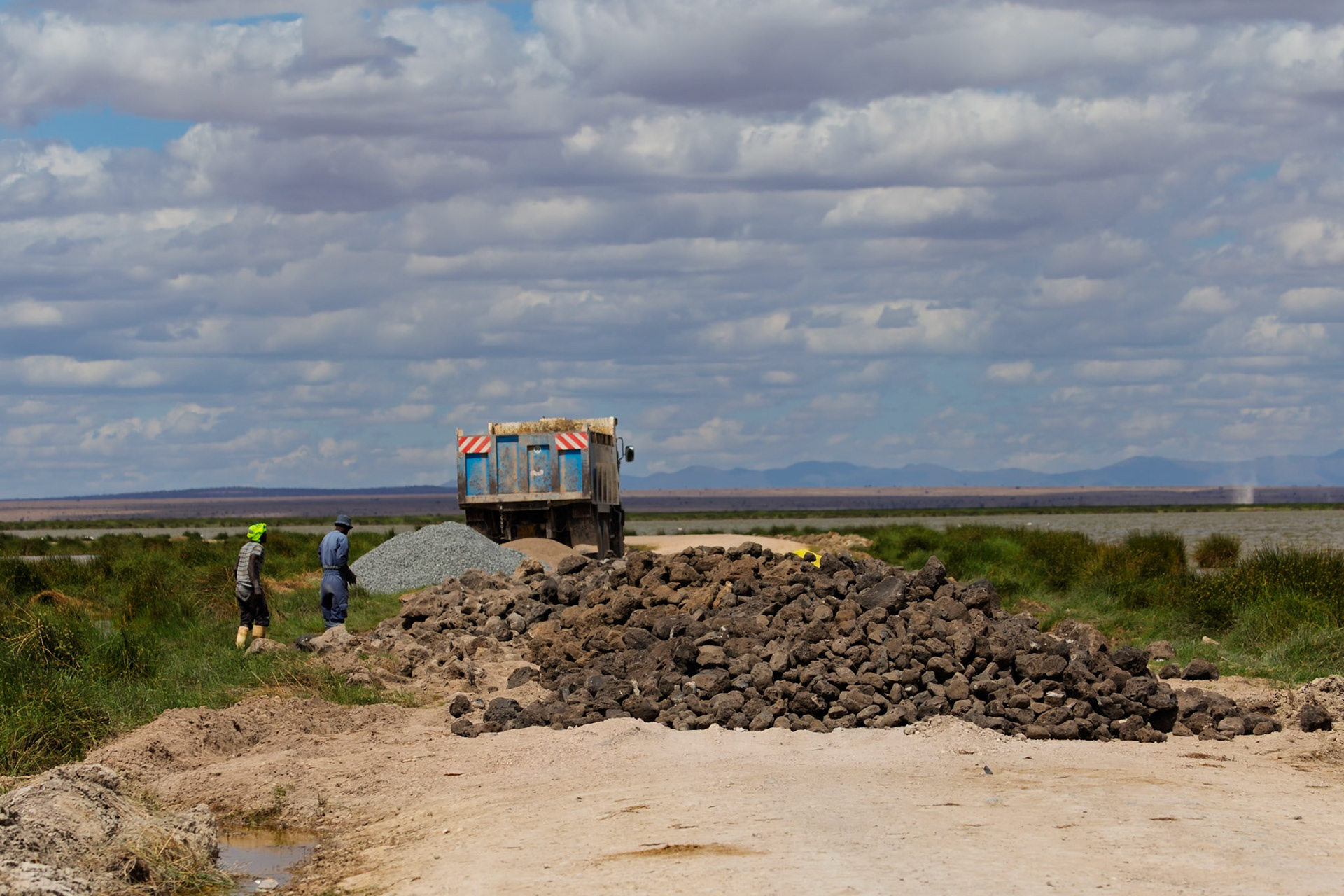 Workers in Kenya's Amboseli National Park unload rocks from a truck for a construction project.