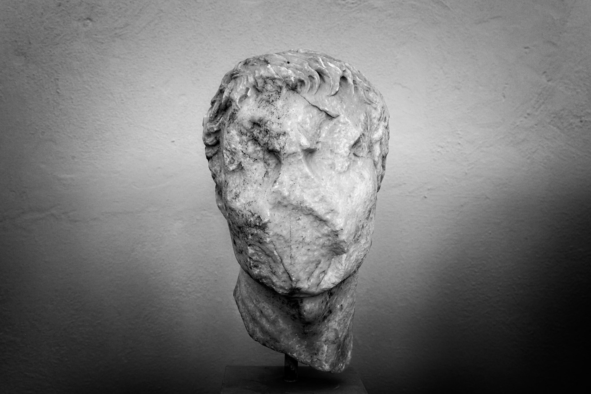 Delos, Greece - May 22nd 2018: A weathered marble head of a man, possibly a deity or important figure, stands as a testament to the island's rich history.