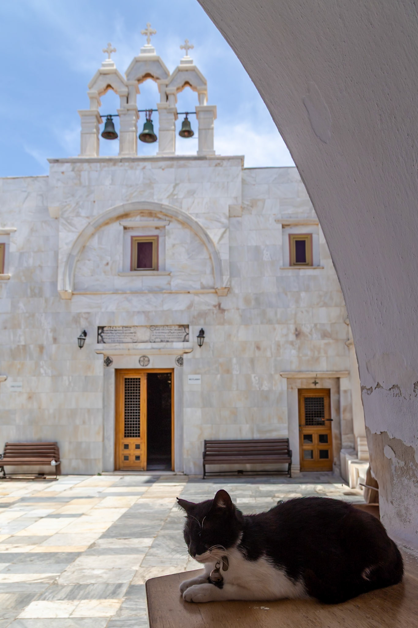 Mykonos, Greece - May 22nd 2018: A cat rests near Panagia Tourliani Monastery, seeking shade and a quiet spot in the courtyard.