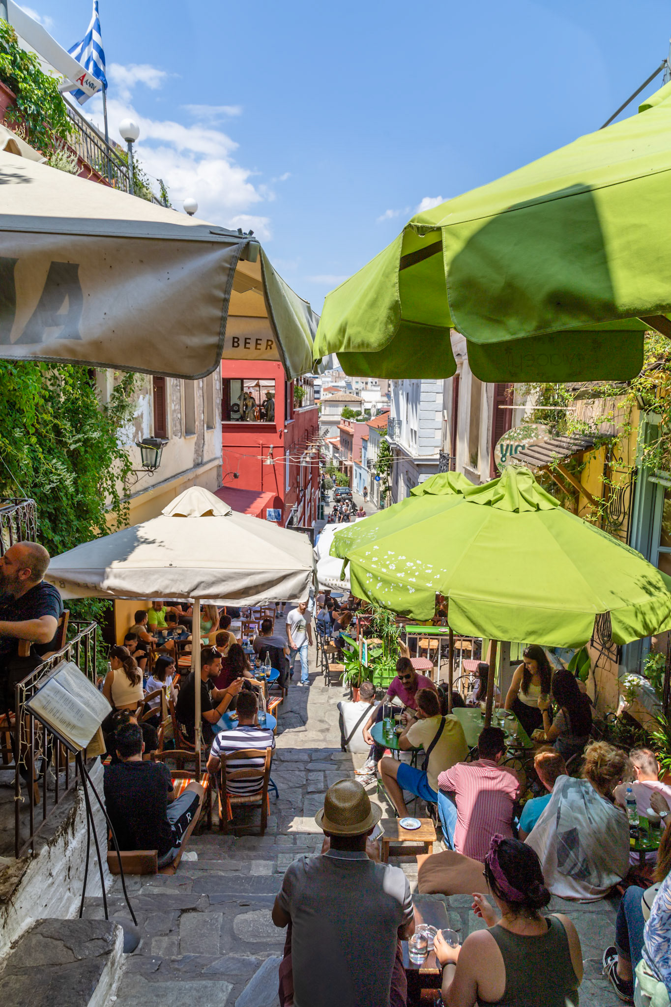 Athens, Greece - May 23rd 2018: People are enjoying food and drinks at a restaurant with outdoor seating on a sunny day in Athens, Greece.