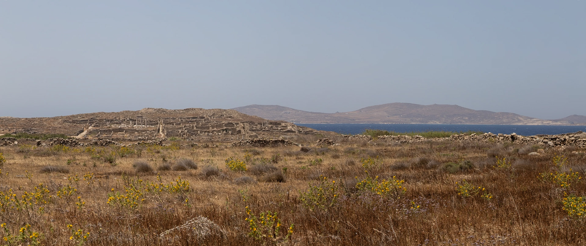 Delos, Greece - May 22nd 2018: An image of the ruins of Delos, a Greek island and archaeological site, showing the ancient city's layout and surrounding landscape.