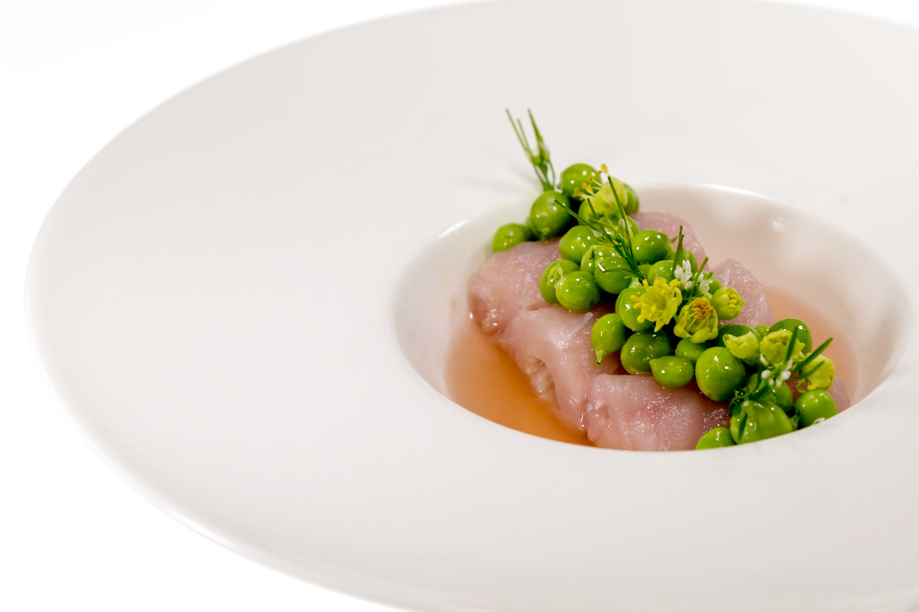 Fog Lark, Portland, Oregon - April 6th 2018: A chef plates a delicate dish of raw fish, peas, and herbs in a light broth for a tasting menu.