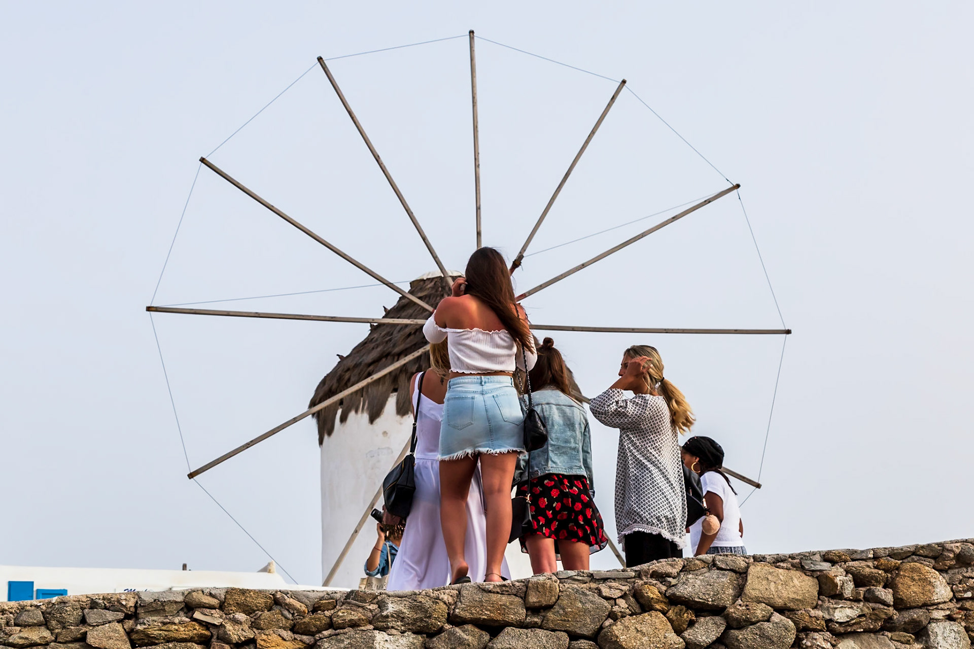Mykonos, Greece - May 23rd 2018: Tourists gather to take pictures of the iconic windmills, a popular attraction on the island.