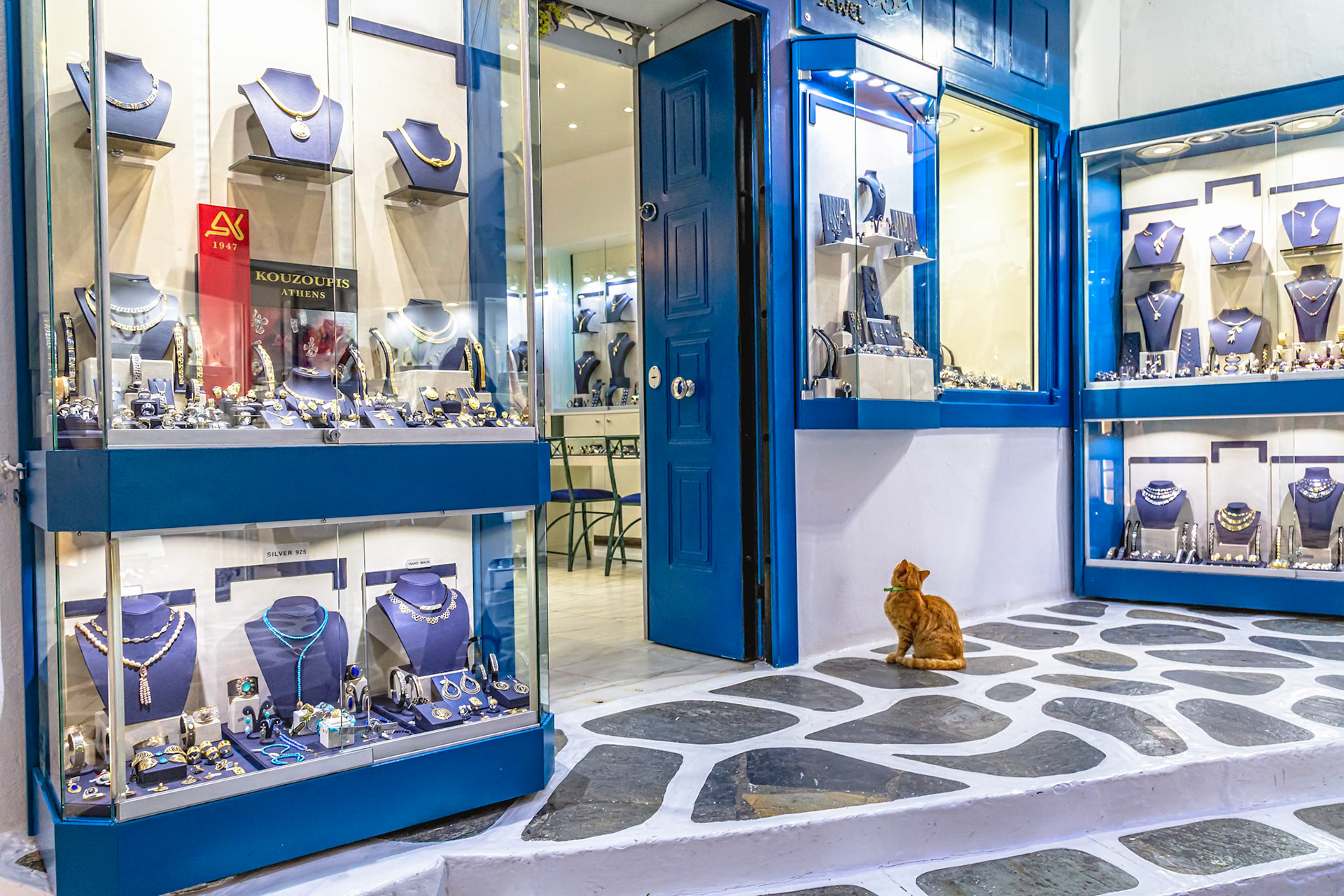 Mykonos, Greece - May 22nd 2018: A ginger cat sits outside a jewelry store, perhaps hoping for a shiny new collar.