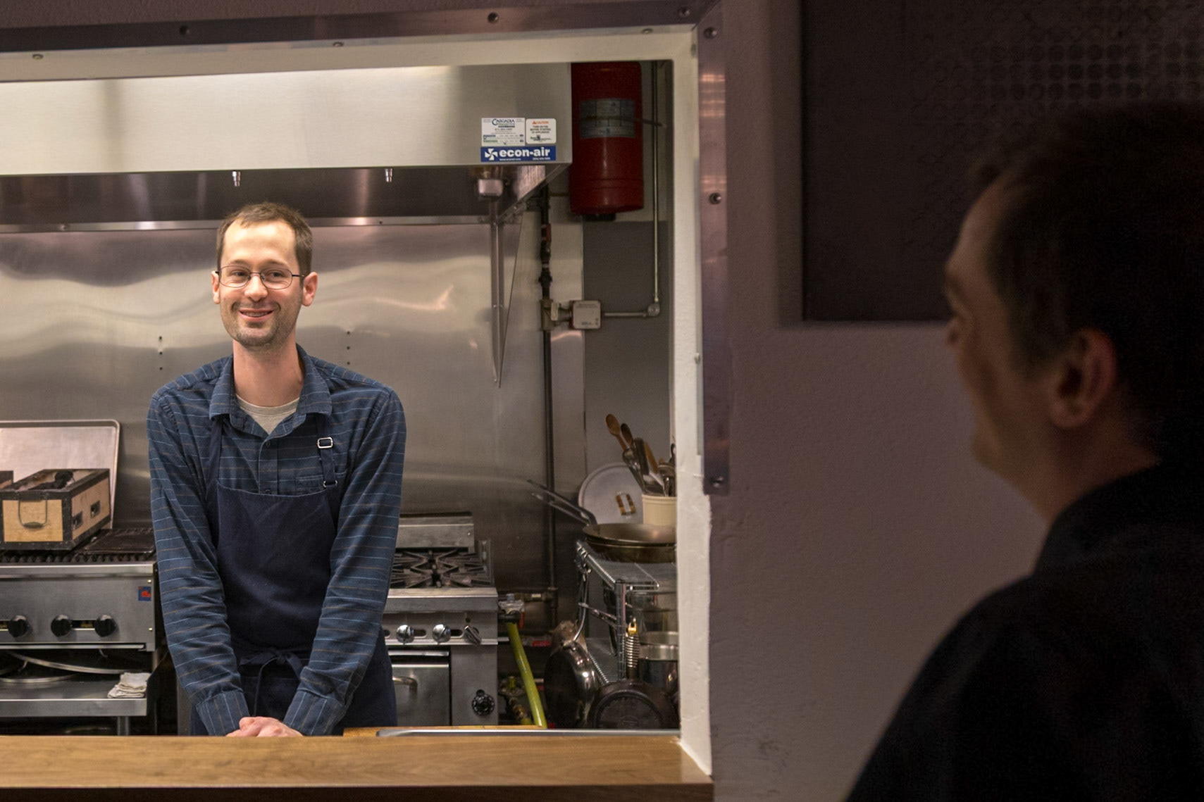 Fog Lark, Portland, Oregon - April 6th 2018: A chef smiles from the kitchen, ready to serve customers at Fog Lark restaurant.