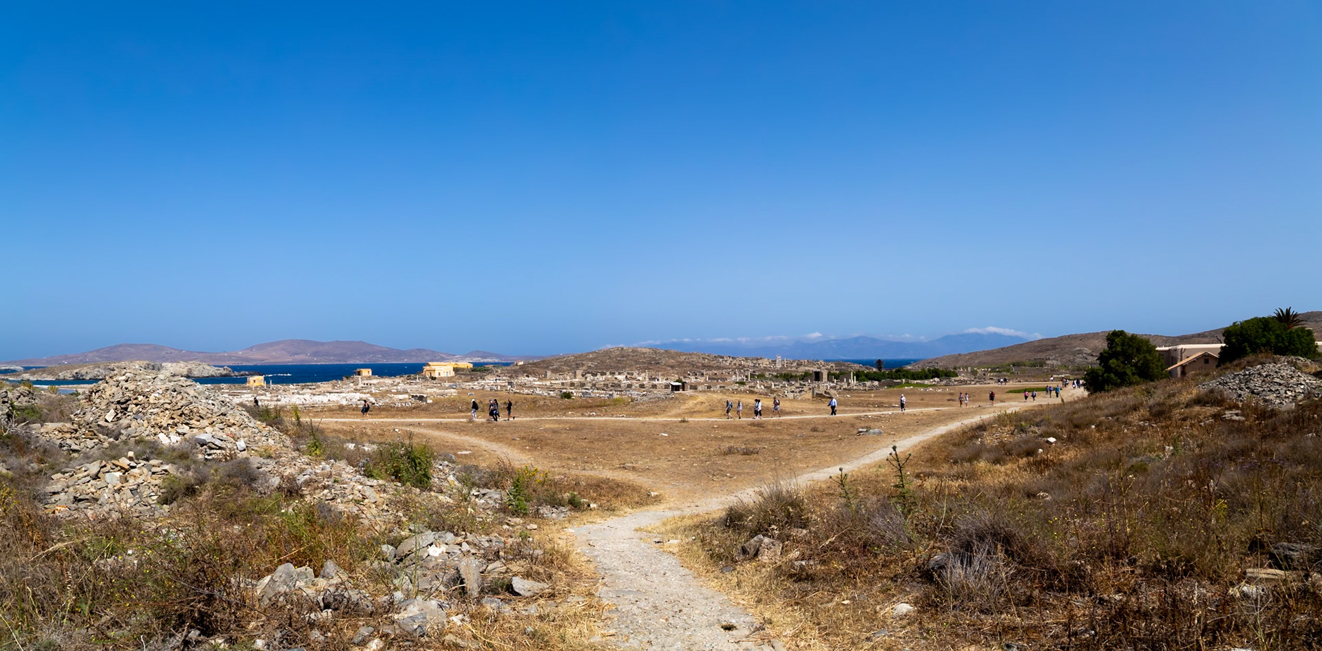 Delos, Greece - May 22nd 2018: Tourists explore the ancient ruins of Delos, a UNESCO World Heritage site, to learn about Greek history and culture.