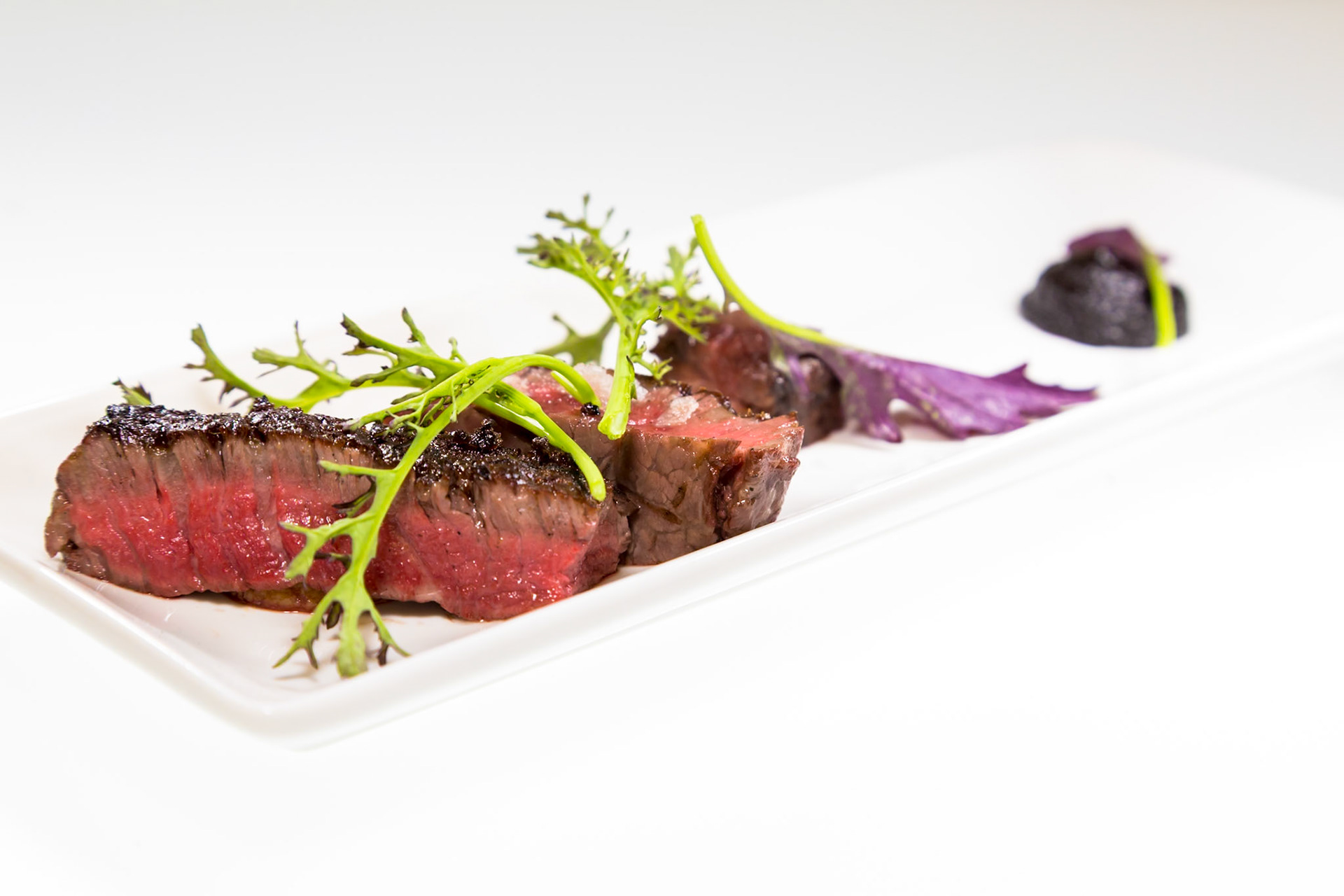 Fog Lark, Portland, Oregon - April 6th 2018: A chef plates a perfectly cooked steak with greens and a dark sauce for a fine dining experience.