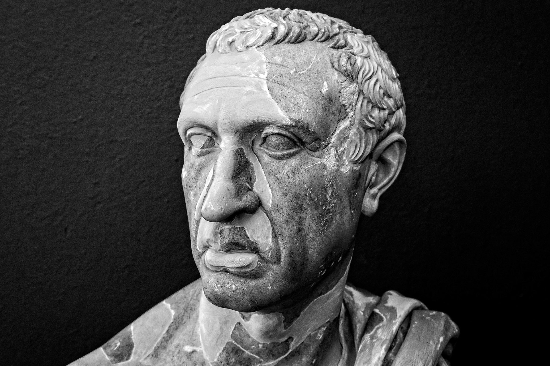 Delos, Greece - May 22nd 2018: A black and white close-up shows a weathered marble bust of a man, possibly a Roman official, displayed at the archeological site.