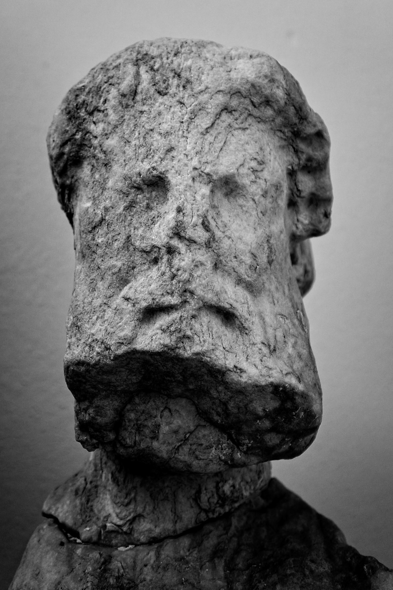 Delos, Greece - May 22nd 2018: A weathered, ancient stone head sculpture stands, its features eroded by time, a silent witness to Delos' rich history.