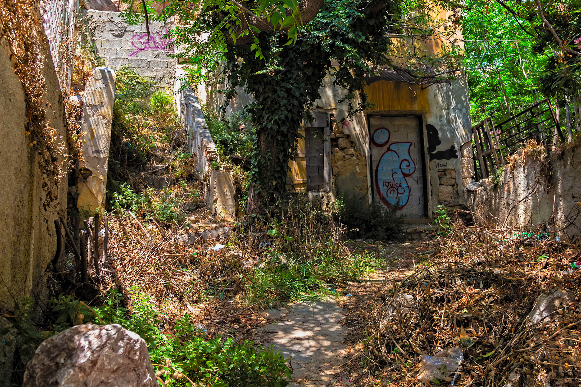 Athens, Greece - May 23rd 2018: An abandoned building is covered in graffiti and overgrown with vegetation, showing urban decay and neglect.