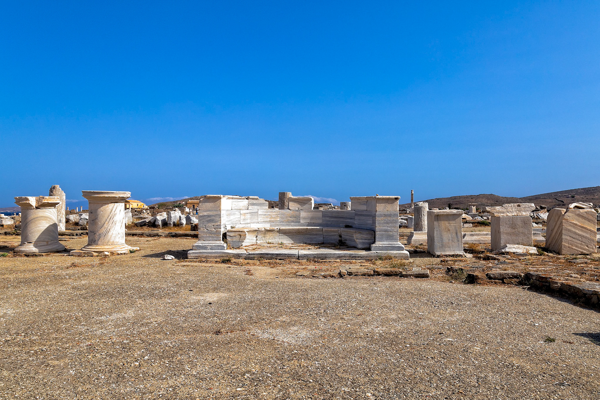 Delos, Greece - May 22nd 2018: Ruins of ancient structures stand against a clear blue sky. These ruins are preserved to show the history of the island.