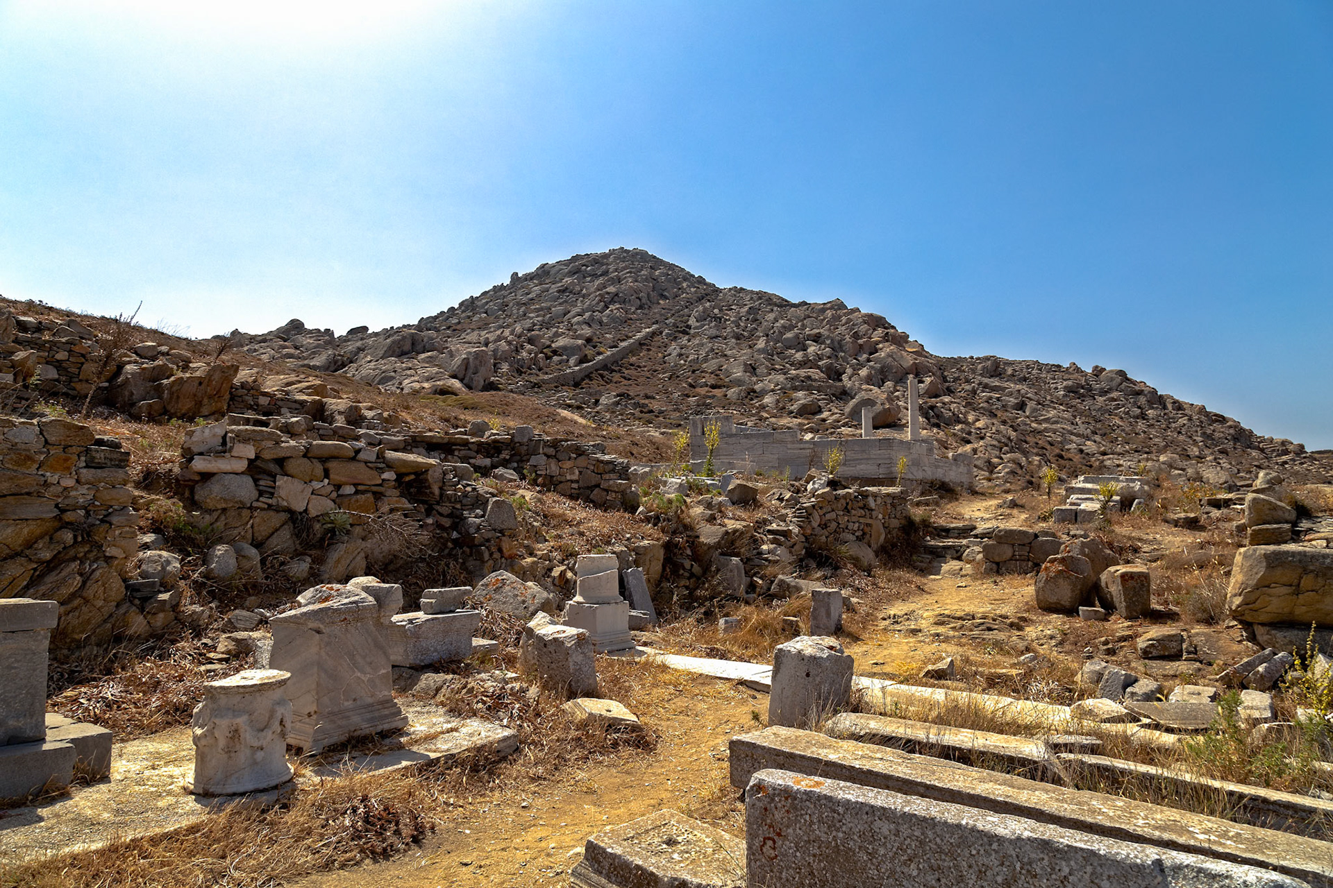 Delos, Greece - May 22nd 2018: Ruins of ancient structures scatter the landscape, remnants of a once-thriving civilization on the island of Delos.