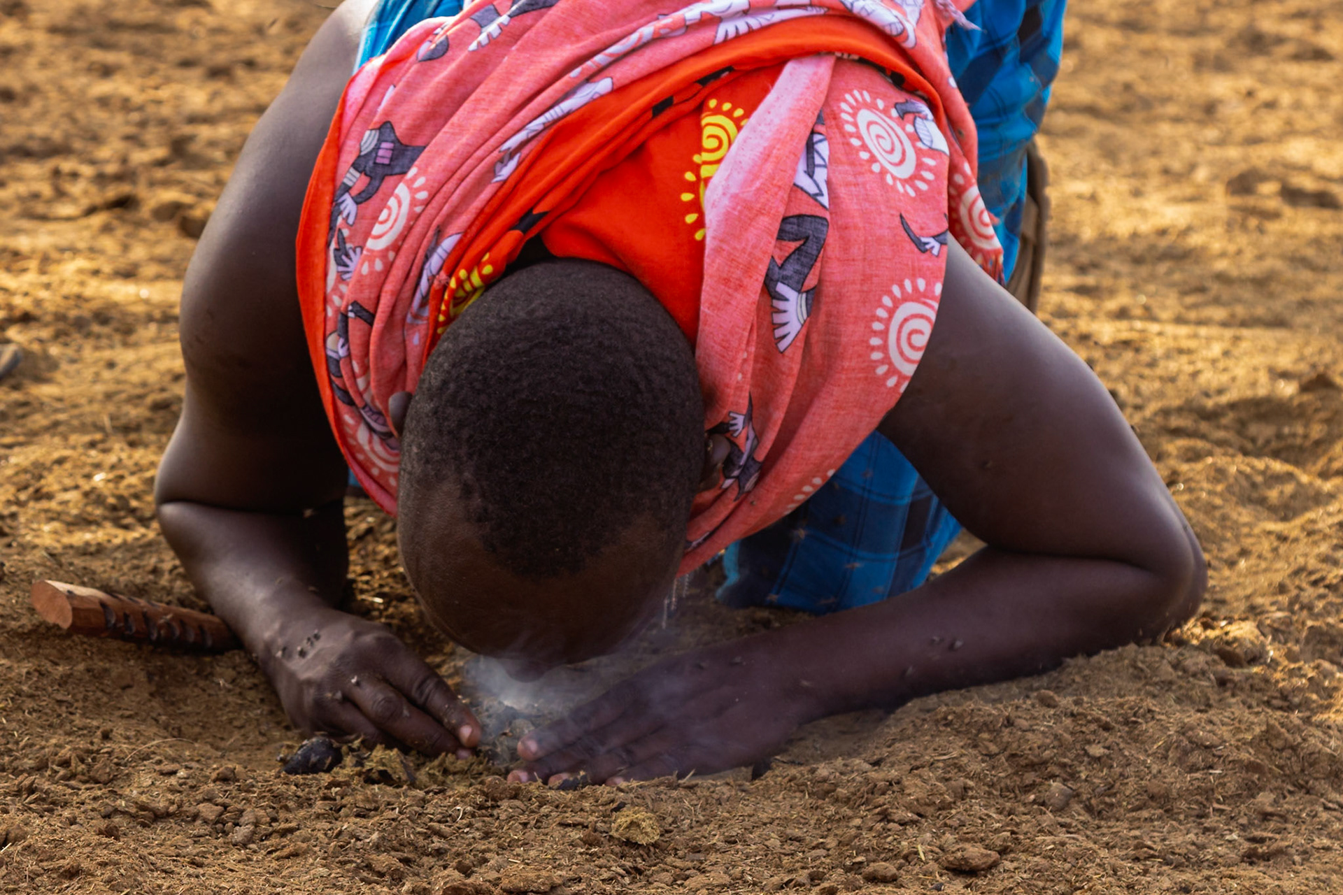 A Maasai man in Kenya uses traditional methods to start a fire in her village.