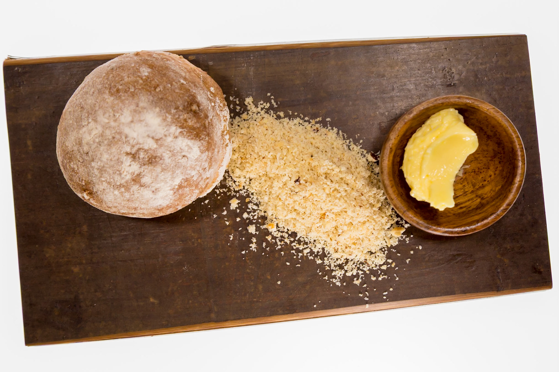 Fog Lark, Portland, Oregon - April 6th 2018: A round loaf of bread, breadcrumbs, and butter are displayed on a wooden board.