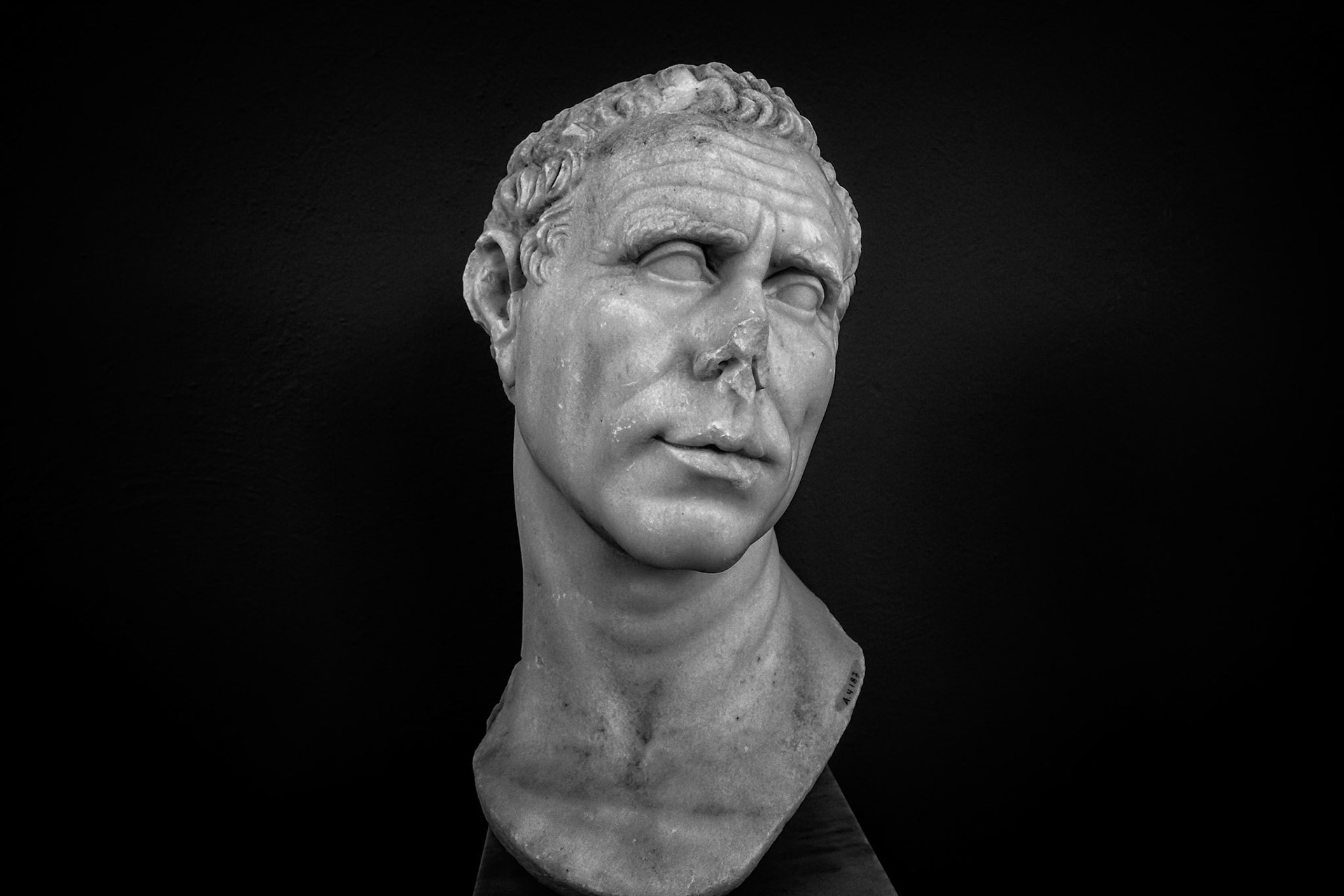 Delos, Greece - May 22nd 2018: A marble bust of a man with a damaged nose is on display. The bust is a historical artifact, showcasing ancient Greek artistry.