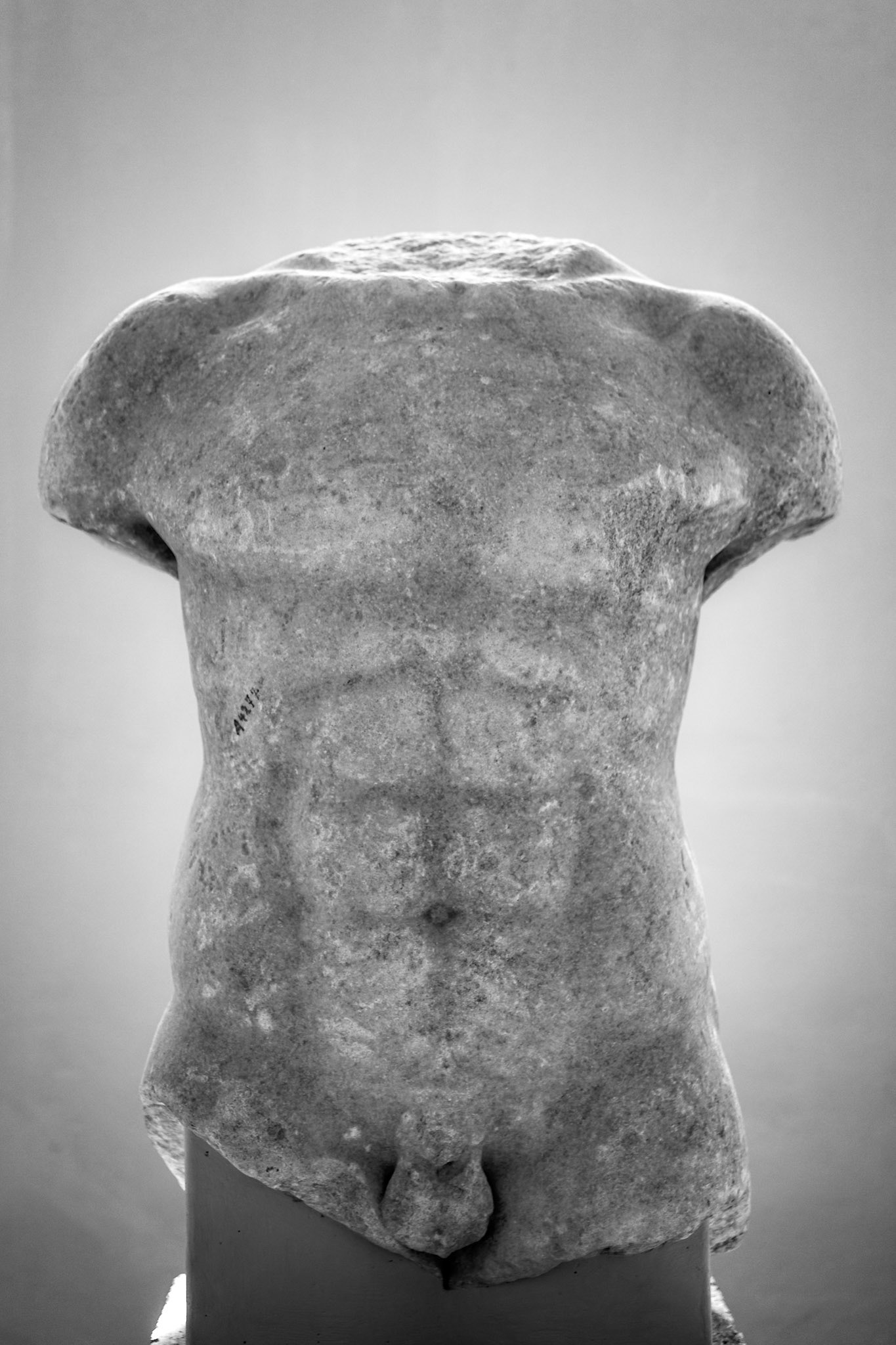 Delos, Greece - May 22nd 2018: A torso of a male statue stands on display. The statue is missing its head and limbs, but the muscular physique is still visible.