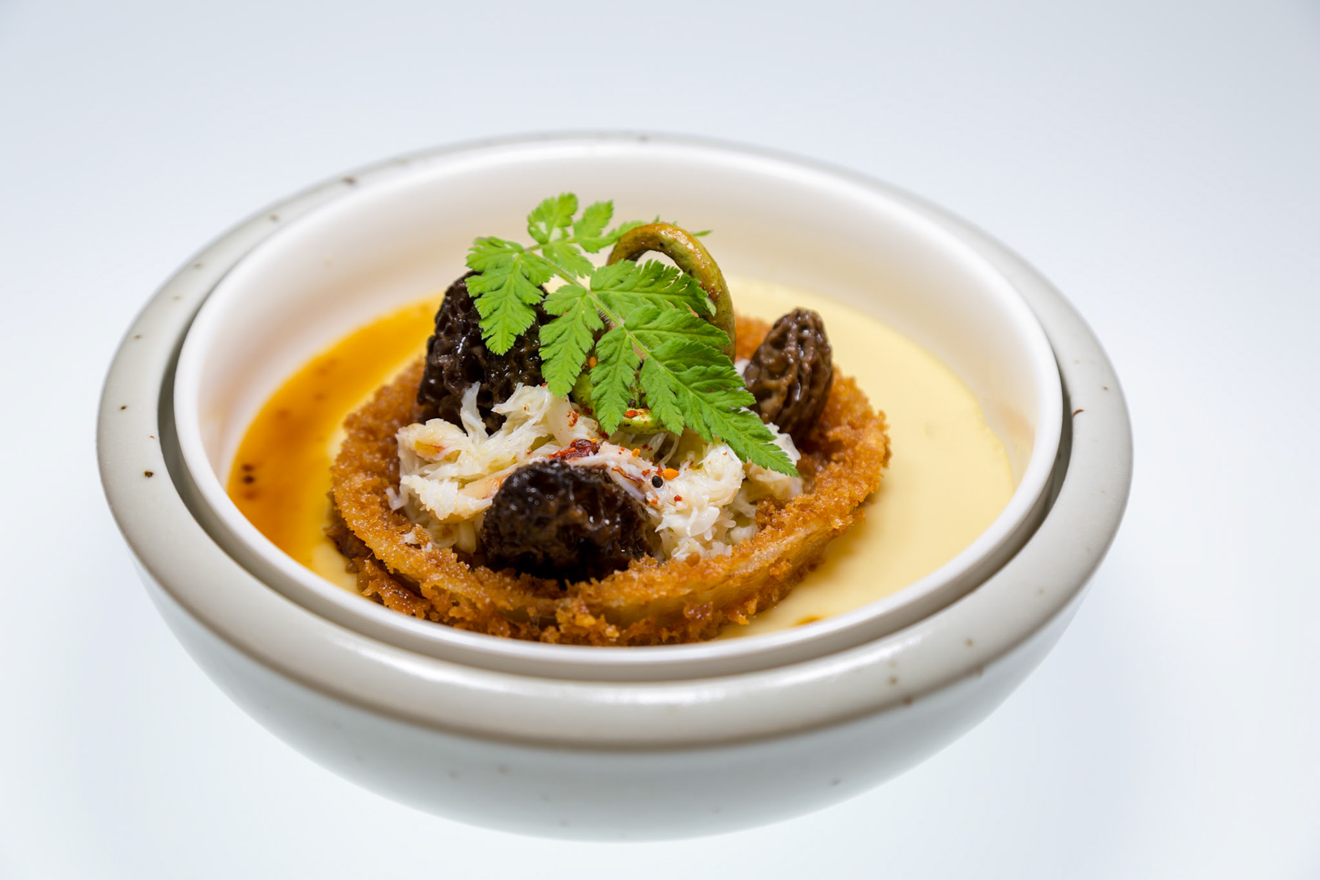 Fog Lark, Portland, Oregon - April 6th 2018: A culinary creation featuring morels, crab, and greens atop a crispy base in a creamy sauce.