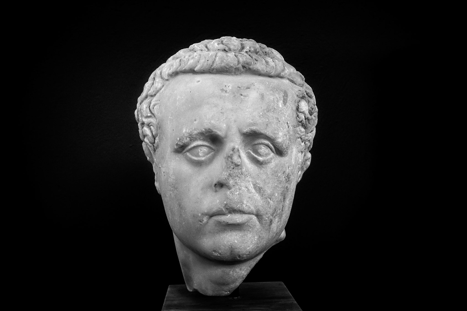 Delos, Greece - May 22nd 2018: A marble head of a man, possibly a Roman official, is displayed. The sculpture shows signs of age and damage.