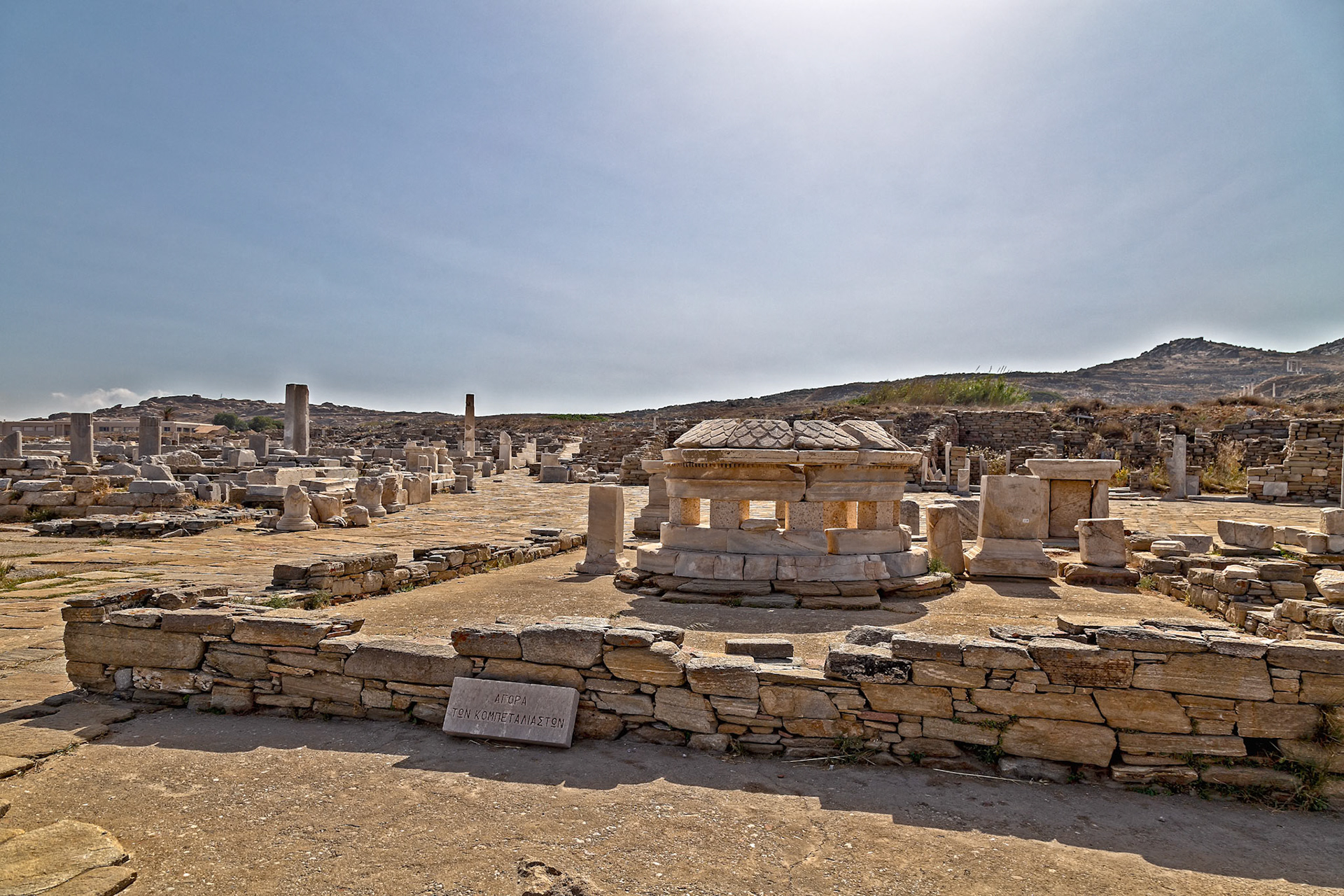 Delos, Greece - May 22nd 2018: Ruins of the Agora of the Competaliasts, a marketplace dedicated to Hermes and other deities, stand as a testament to Delos's rich history.
