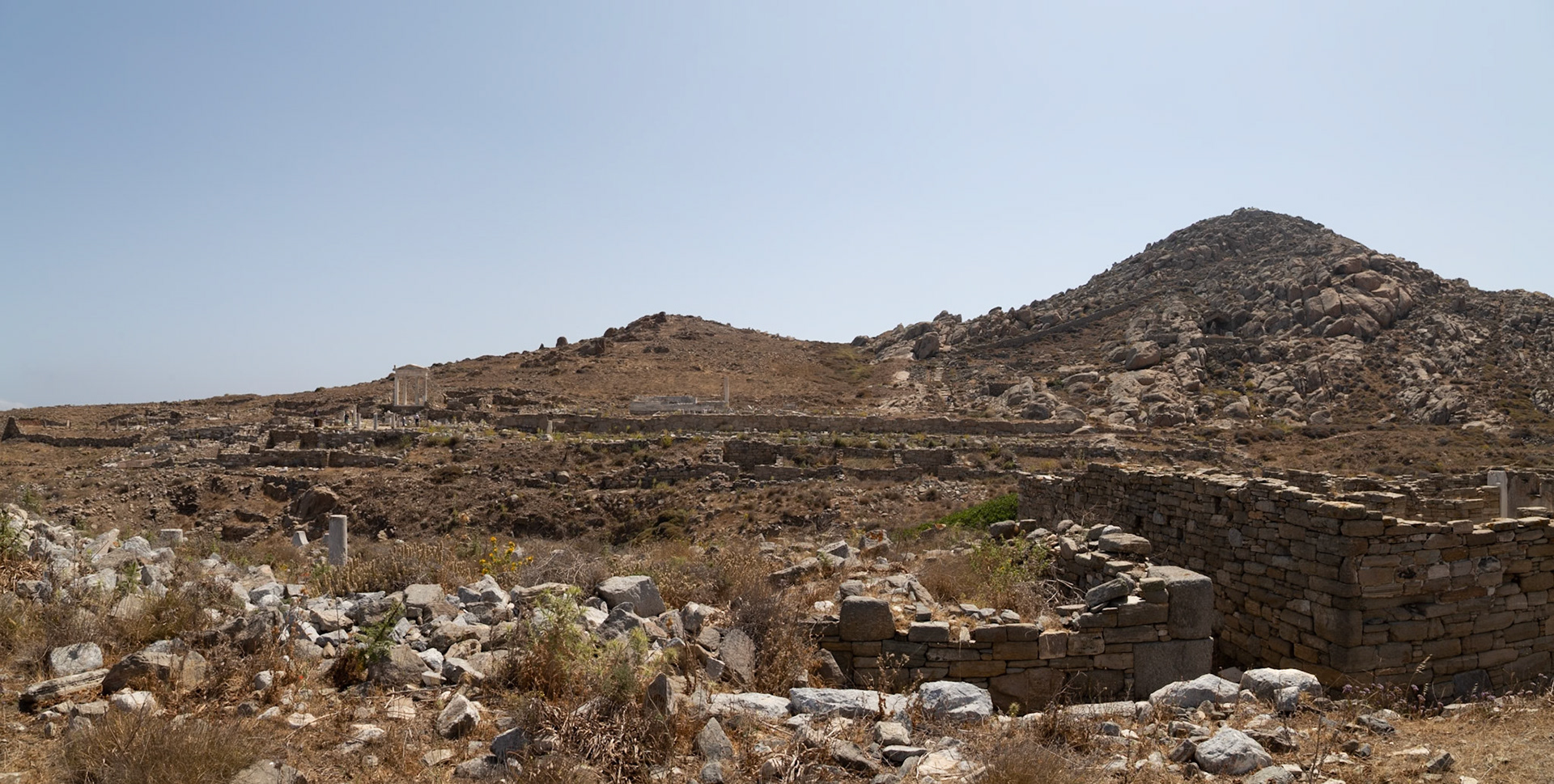 Delos, Greece - May 22nd 2018: Ruins of ancient buildings and structures dot the landscape of Delos, a Greek island and archaeological site, showcasing its rich history.