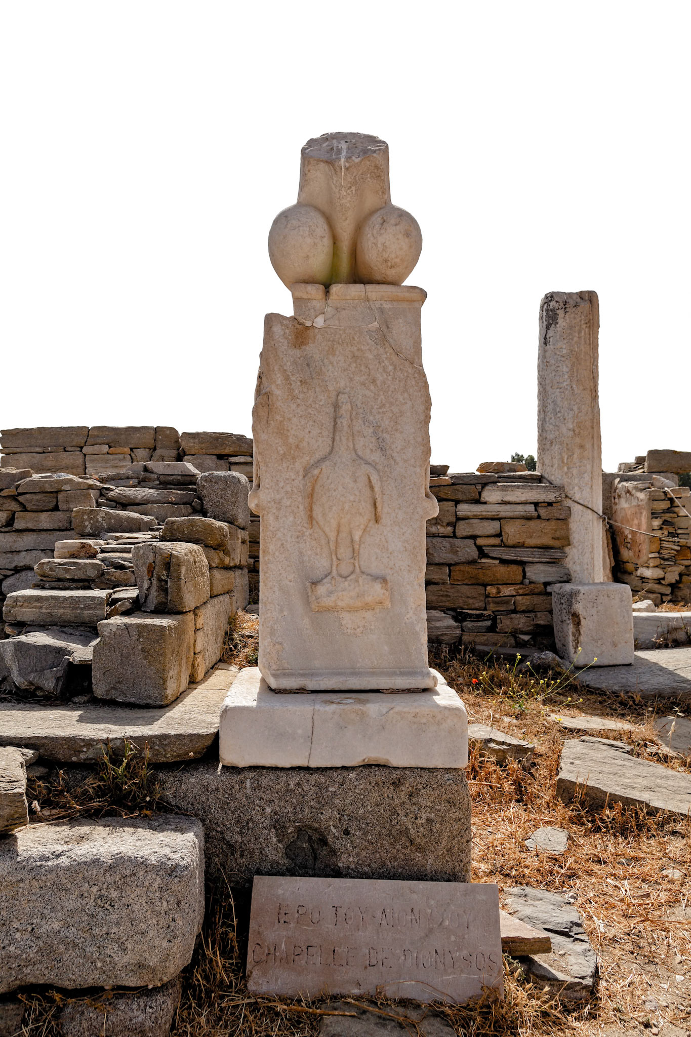 Delos, Greece - May 22nd 2018: A marble stele with a relief of Dionysus' symbol, the phallus, stands at the Chapel of Dionysus, marking the god's presence and worship.