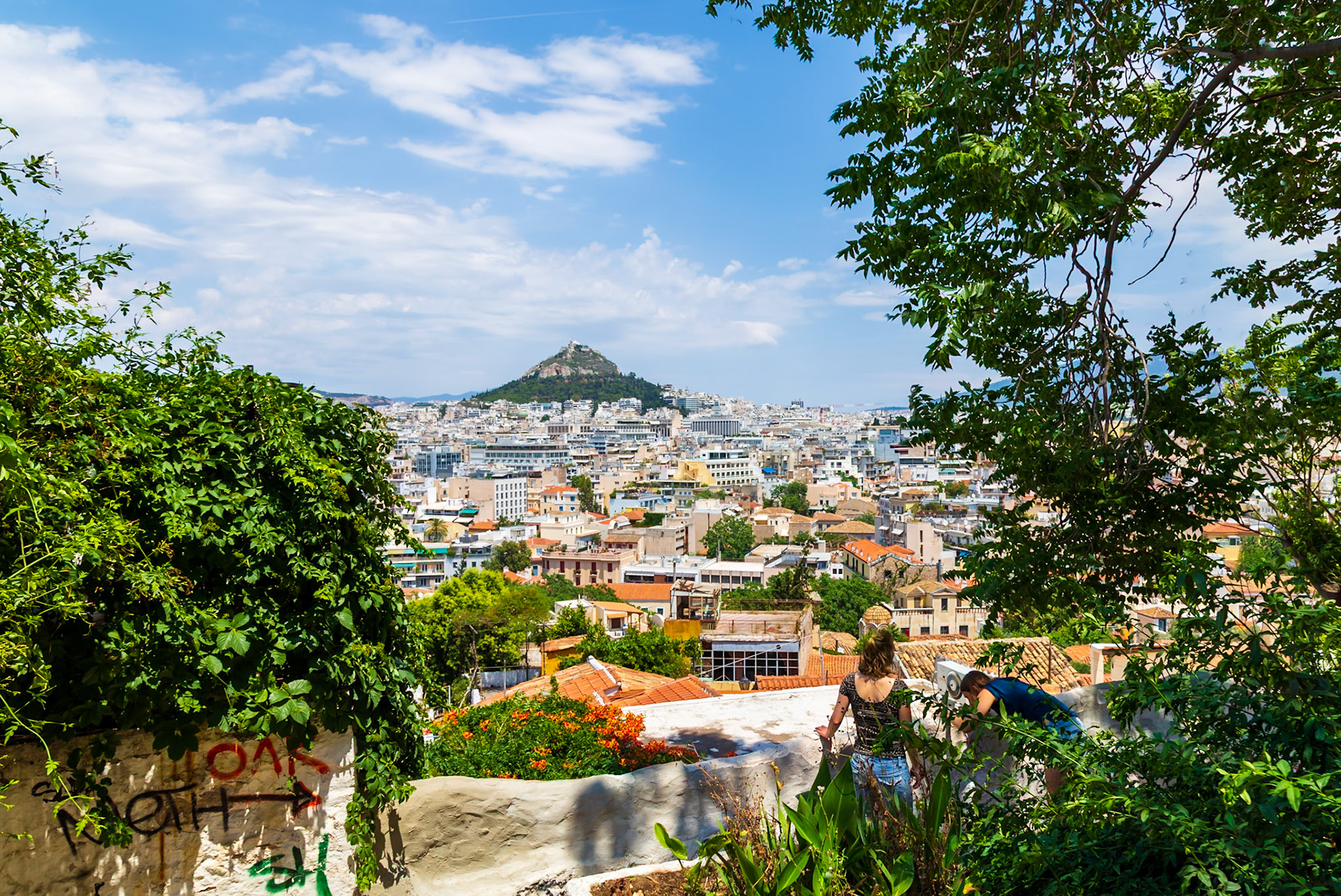 Athens, Greece - May 23rd 2018: Tourists admire the Athens cityscape from a high vantage point, capturing the view with a camera.
