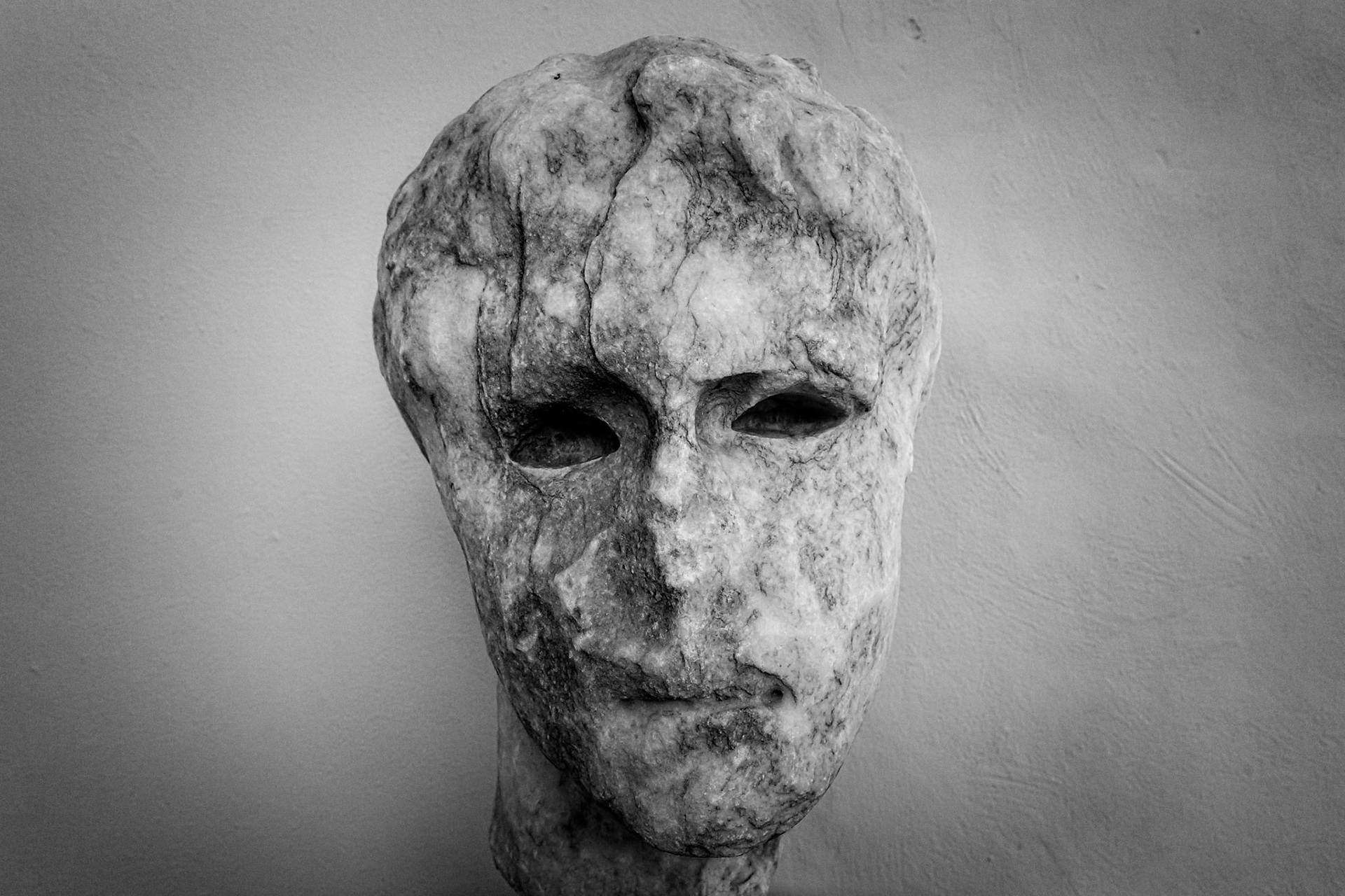 Delos, Greece - May 22nd 2018: A weathered marble head stands as a testament to ancient artistry, its hollow eyes hinting at stories from a bygone era.