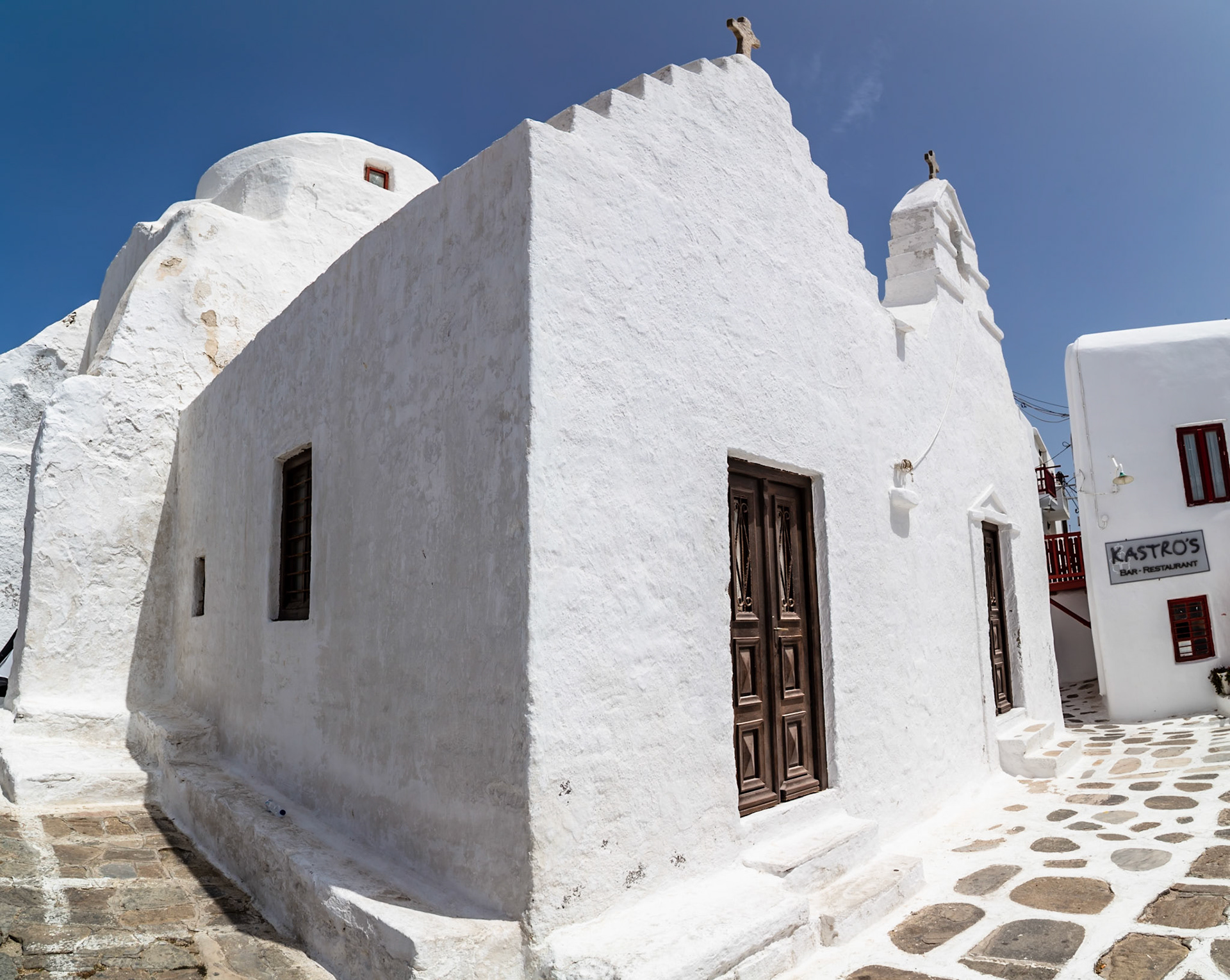 Mykonos, Greece - May 23rd 2018: A traditional whitewashed church stands proudly against the clear blue sky, showcasing Cycladic architecture.