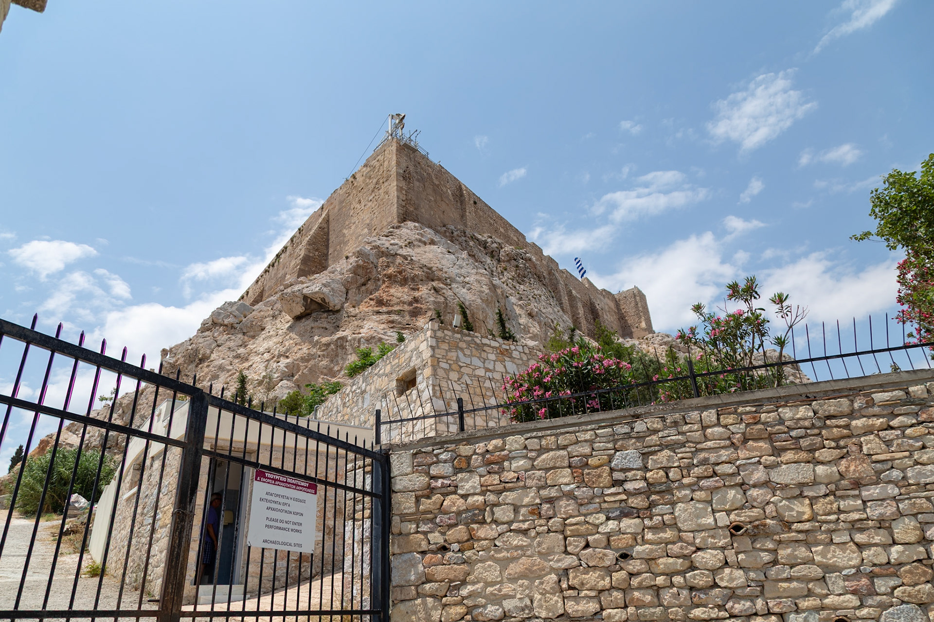 Athens, Greece - May 23rd 2018: A view of the Acropolis from behind a gate with a sign indicating archaeological work is in progress, restricting entry.