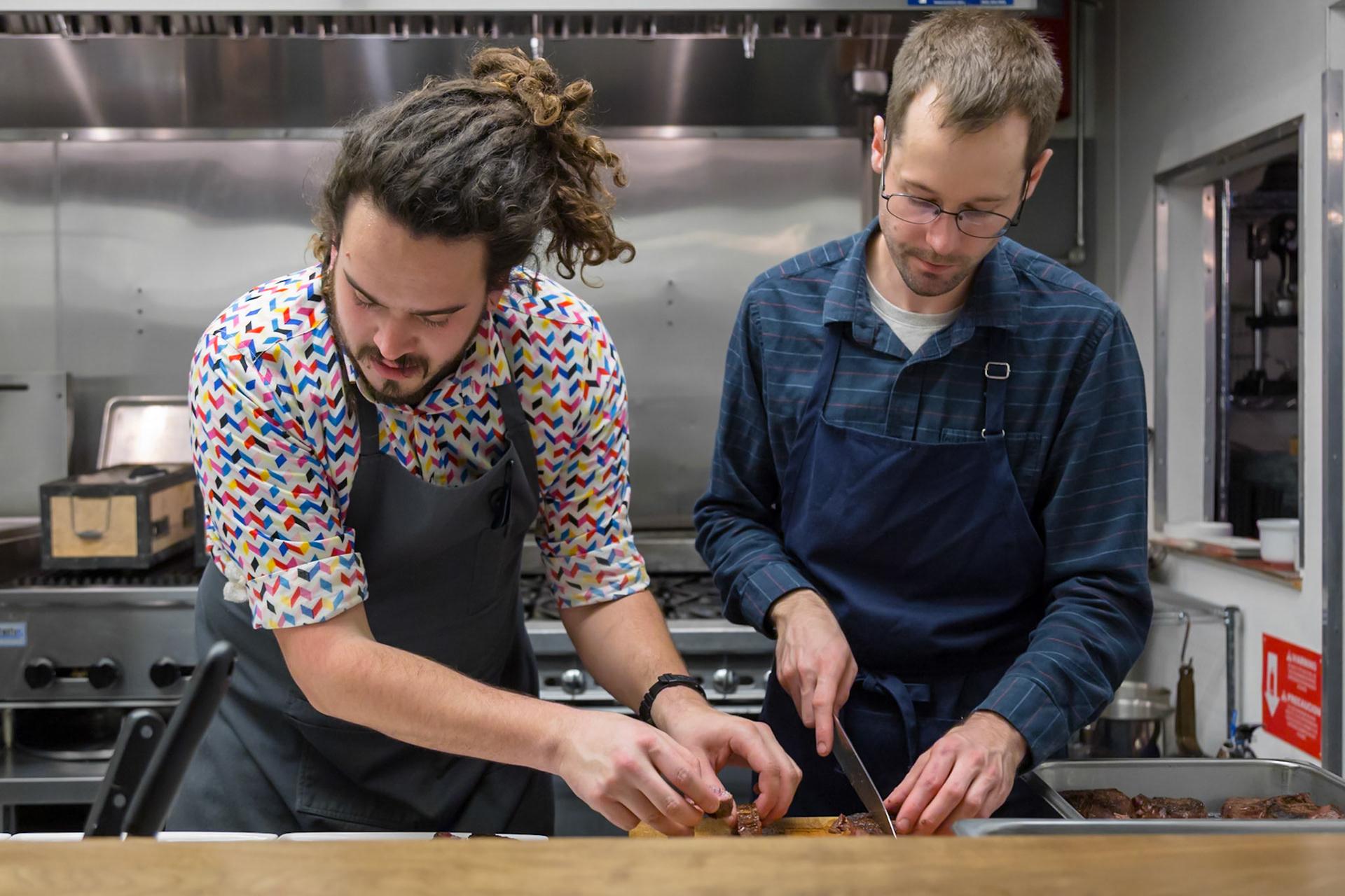 Fog Lark, Portland, Oregon - April 6th 2018: Two chefs are slicing meat in a professional kitchen, preparing for service.