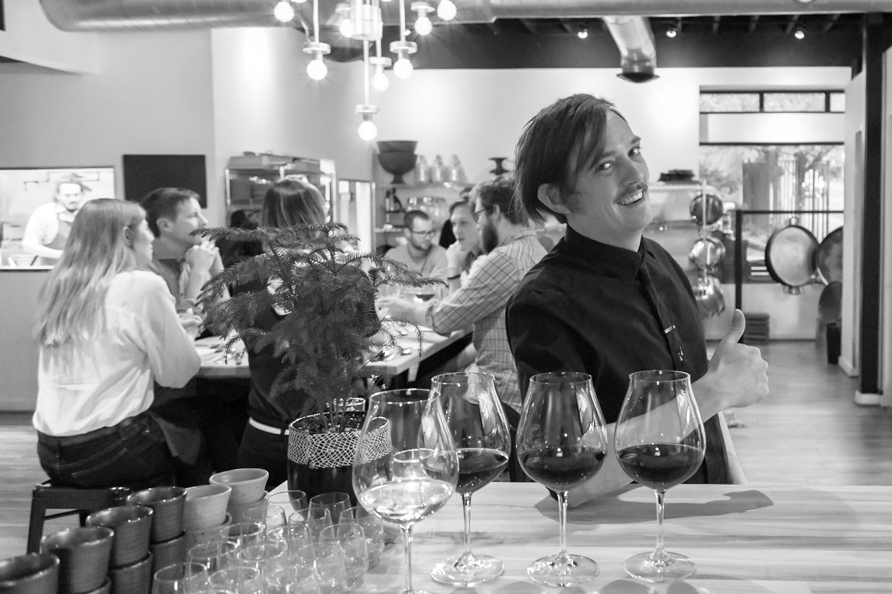Fog Lark, Portland, Oregon - April 6th 2018: A server gives a thumbs up at a wine tasting event with guests enjoying wine at tables.
