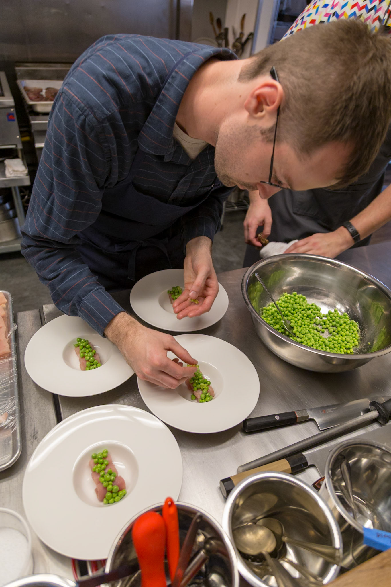 Fog Lark, Portland, Oregon - April 6th 2018: Chefs meticulously plate a dish with fresh peas, ensuring each plate is perfect for service.