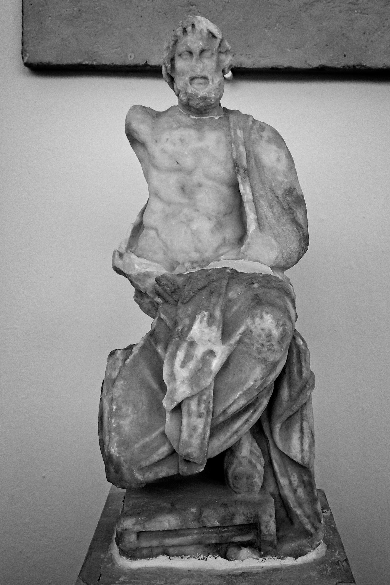 Delos, Greece - May 22nd 2018: A weathered marble statue of a male figure, possibly a god or hero, stands on display, showcasing ancient Greek artistry.