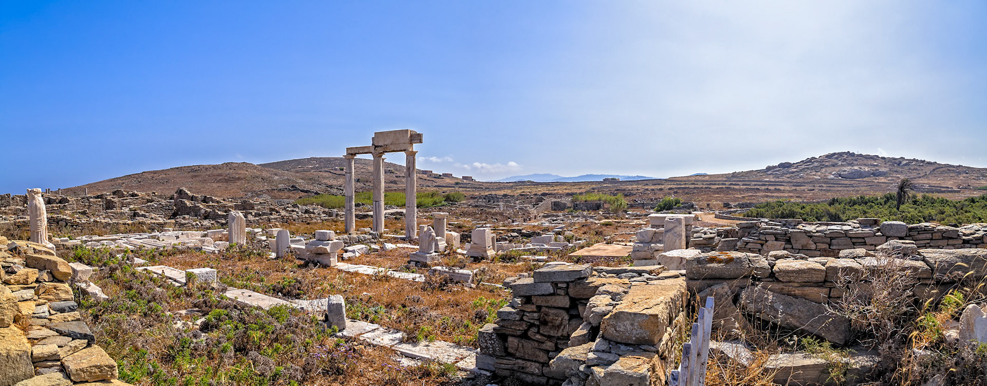 Delos, Greece - May 22nd 2018: Ruins of ancient structures stand on Delos, a Greek island and archaeological site. The site attracts historians and tourists.
