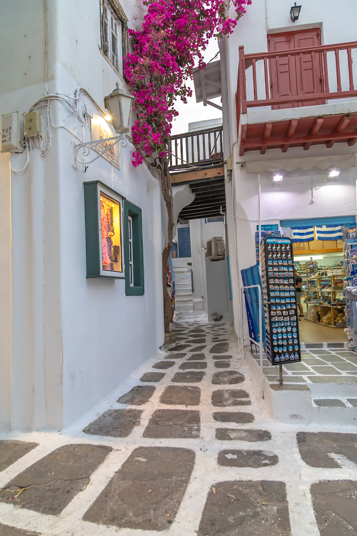 Mykonos, Greece - May 23rd 2018: A narrow street with white buildings and a souvenir shop, showcasing the island's architecture and tourism.