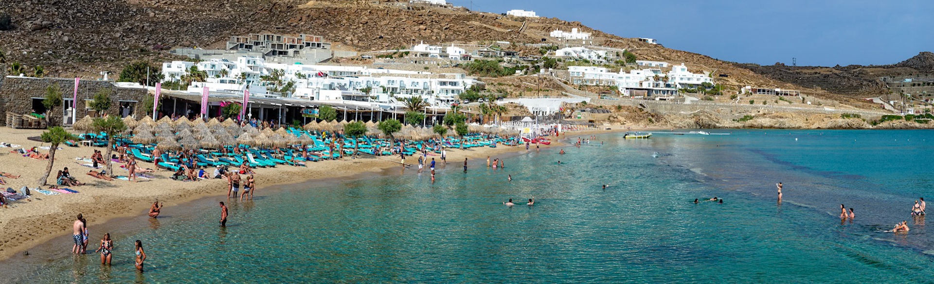 Paradise Beach, Mykonos, Greece - May 24th 2018: Beachgoers relax on the sand and swim in the clear water, enjoying the sun and the vibrant atmosphere.