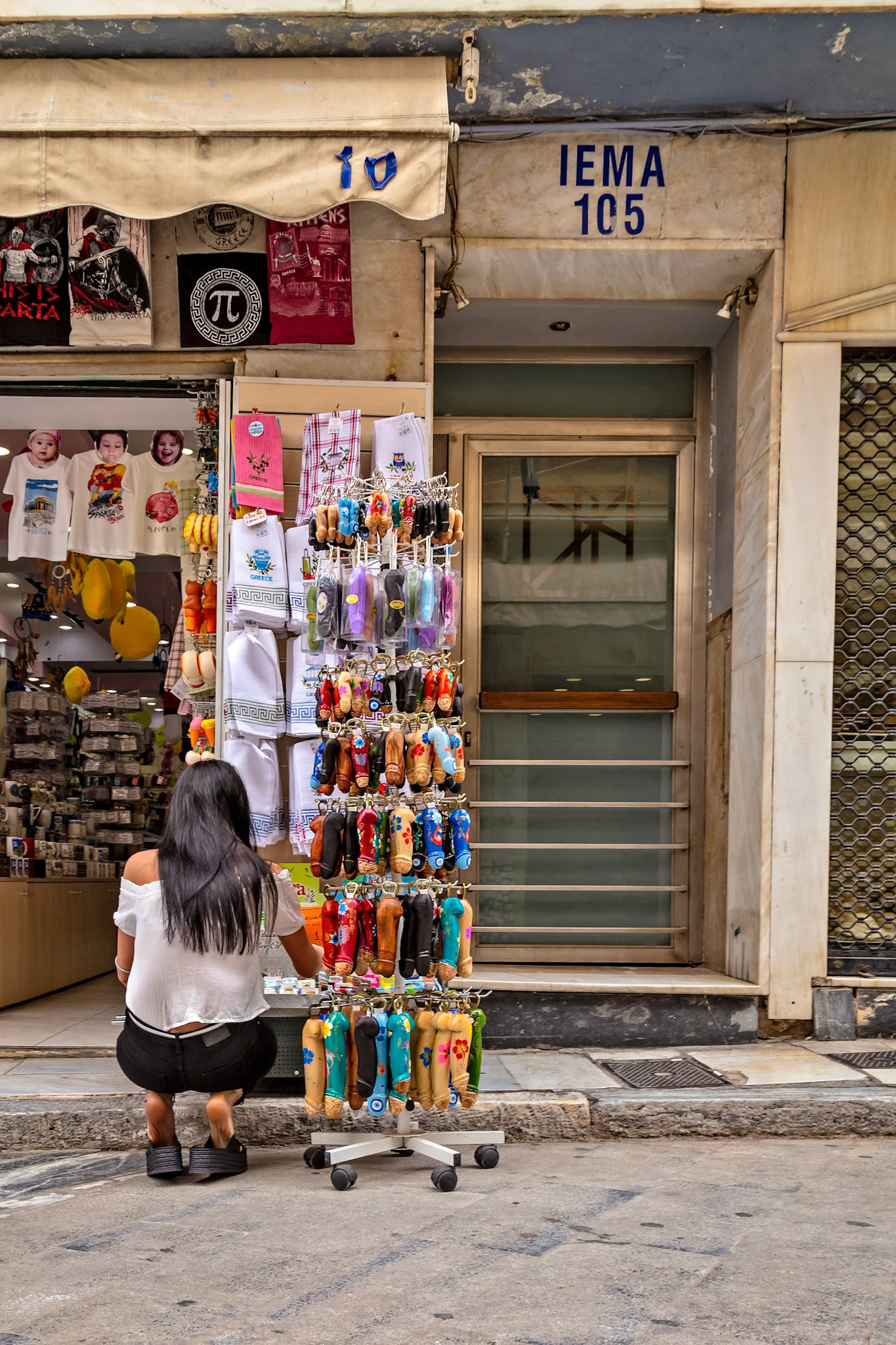 Athens, Greece - May 23rd 2018: A woman shops at a souvenir store, browsing keychains. She is likely a tourist looking for a memento of her trip.